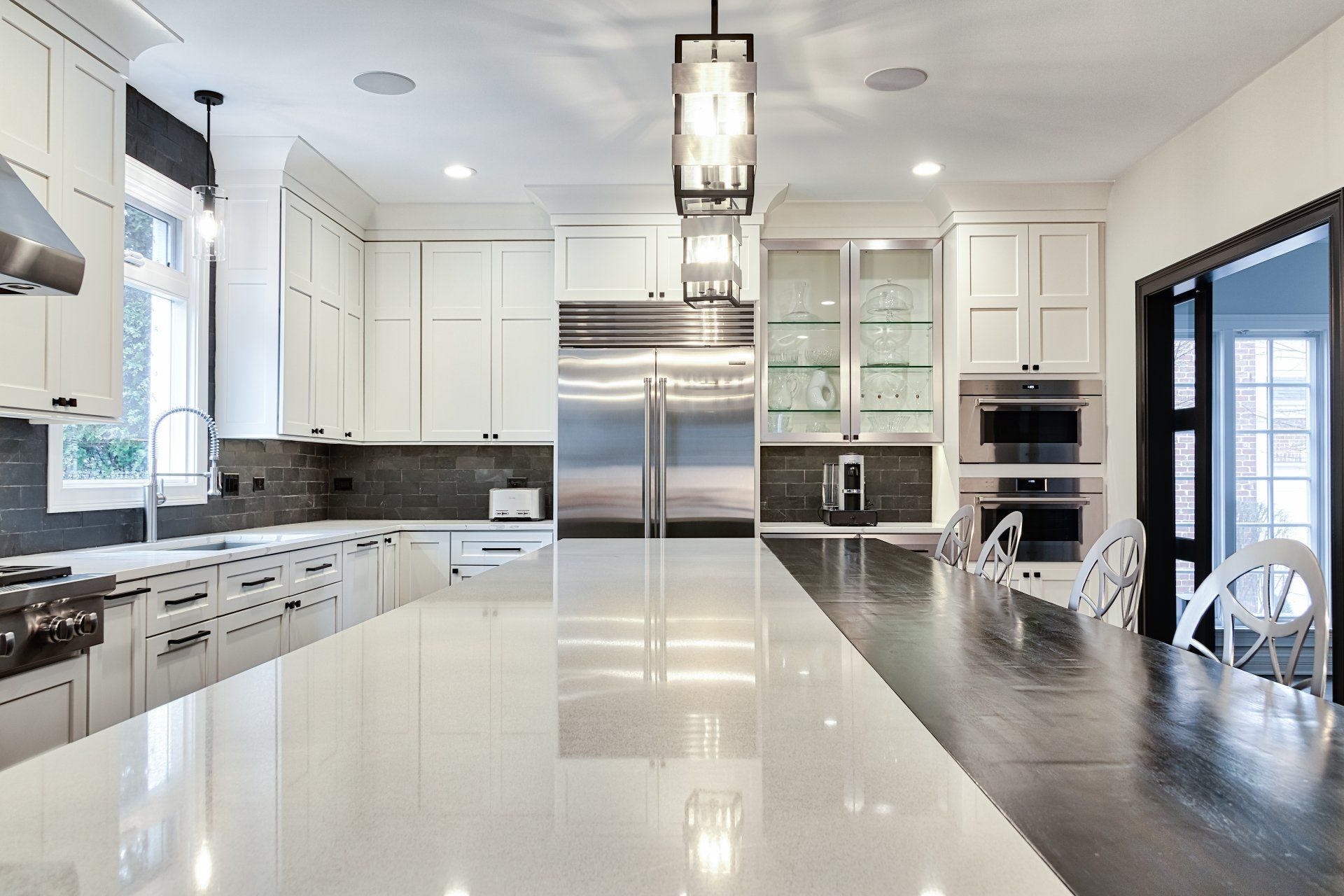 A kitchen with white cabinets and stainless steel appliances and a large island.