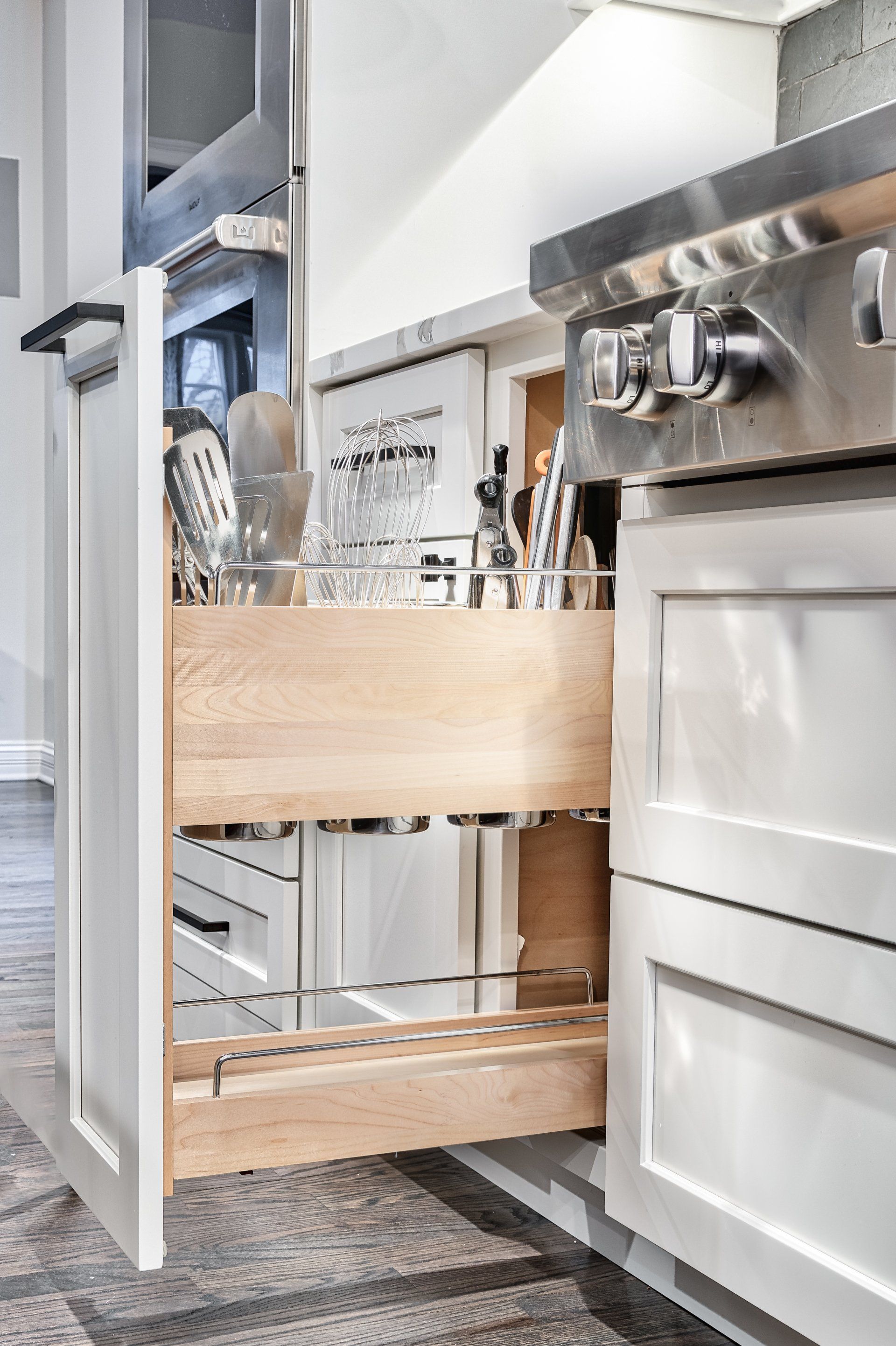 A kitchen with a pull out drawer filled with utensils.