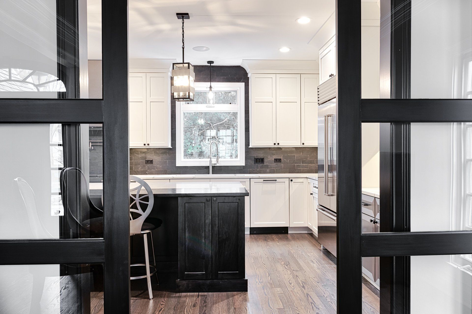 A kitchen with a black island and white cabinets and sliding glass doors.