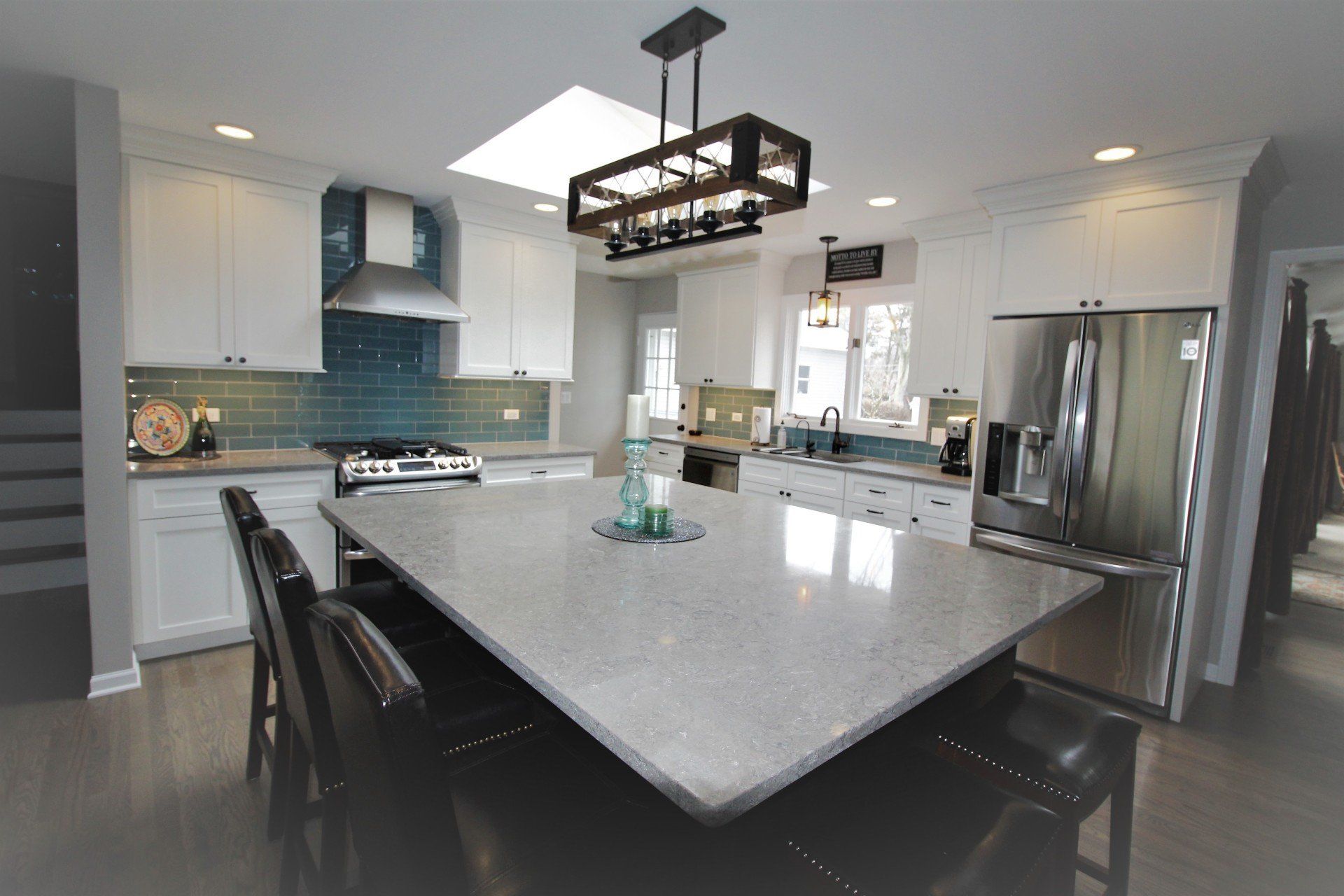 A kitchen with a large island in the middle and stainless steel appliances.