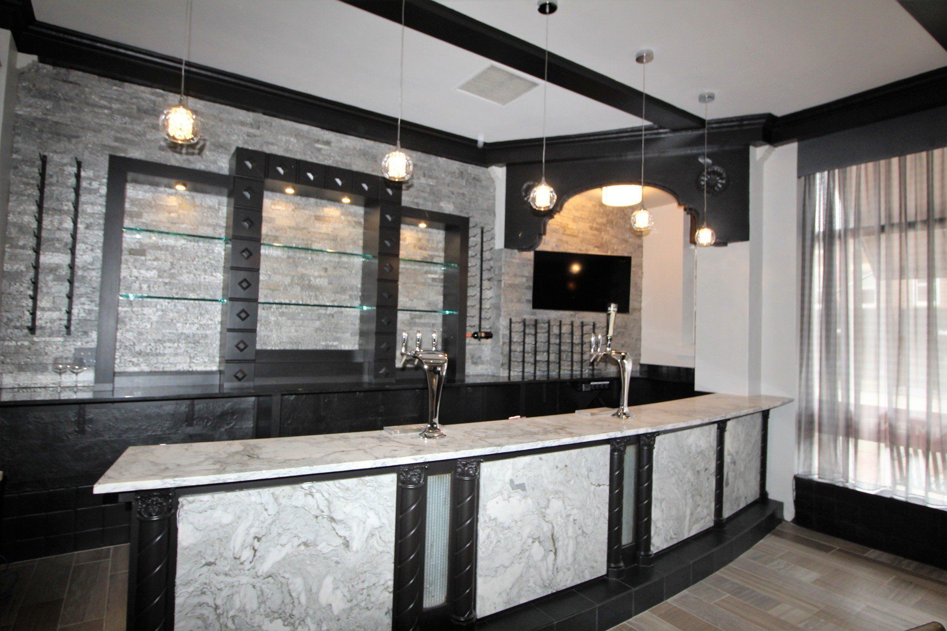A bar with a marble counter top and a television on the wall.