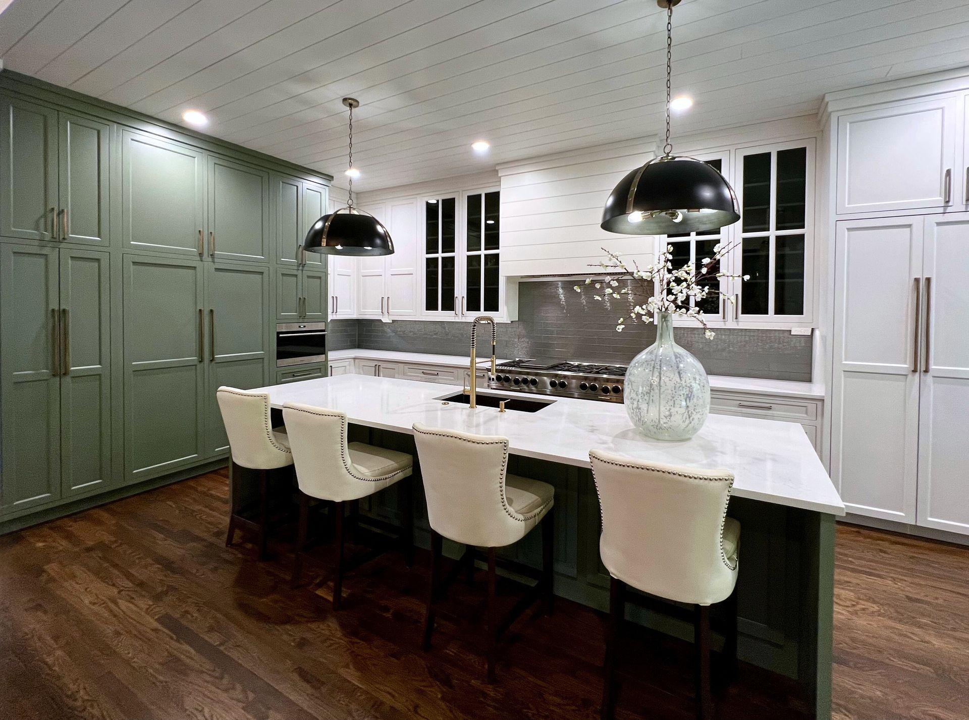 A kitchen with green cabinets , white cabinets , and a large island.