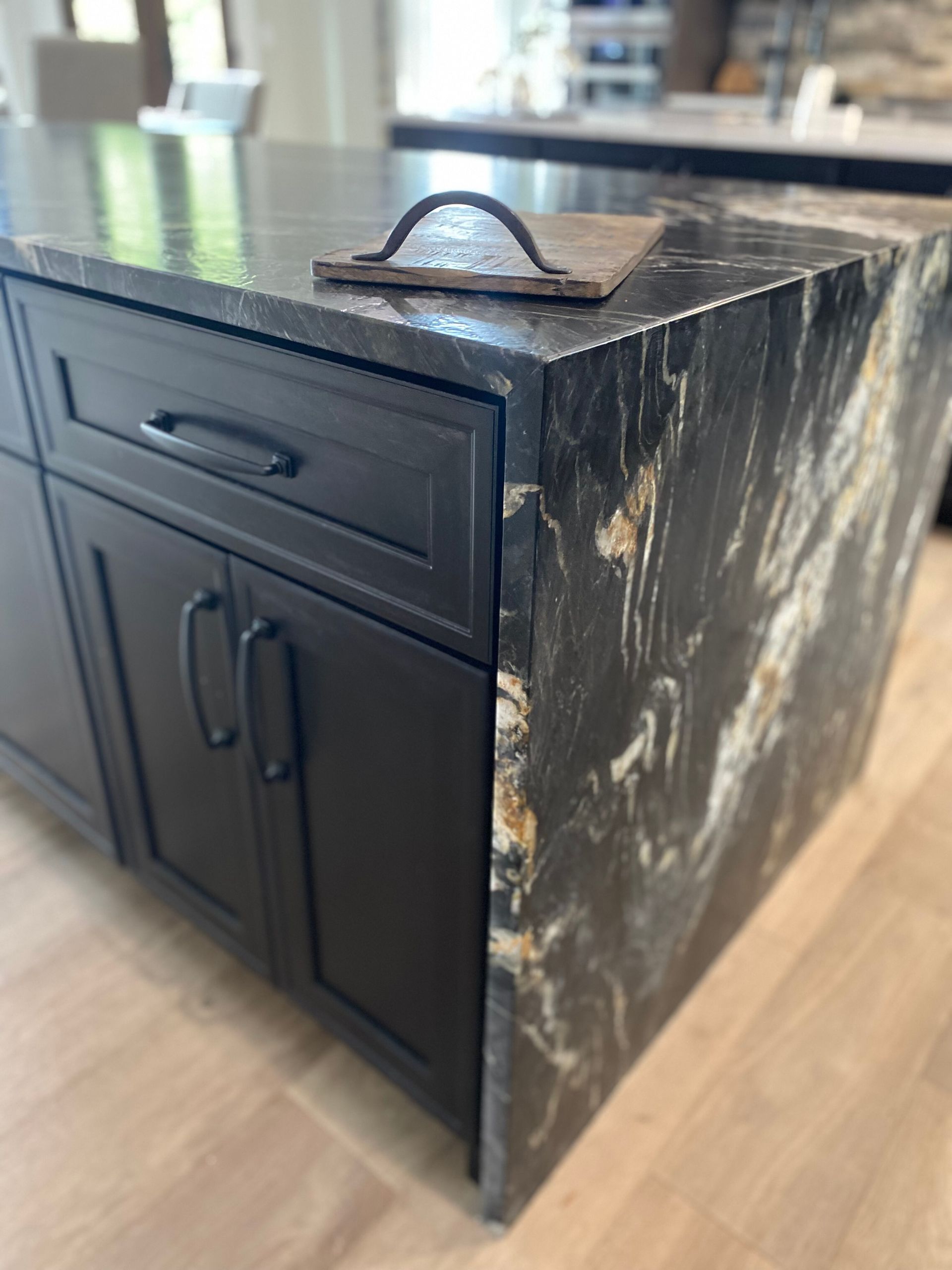 A kitchen island with black cabinets and a black granite counter top.