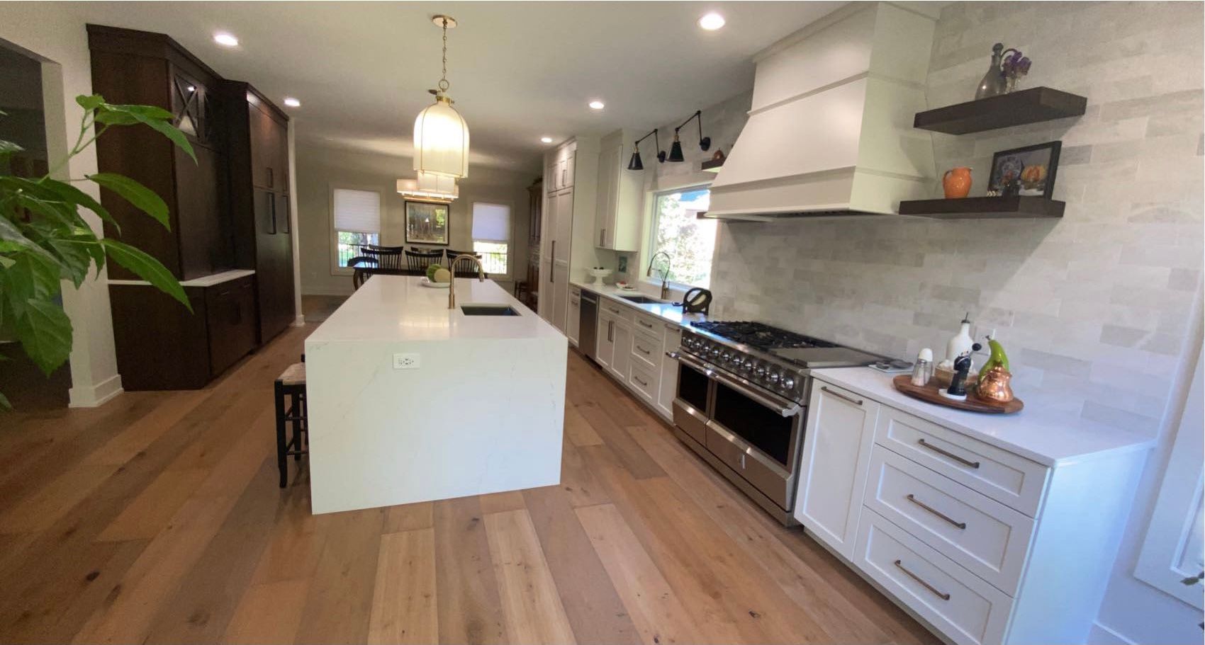 A kitchen with white cabinets , stainless steel appliances , and a large island.