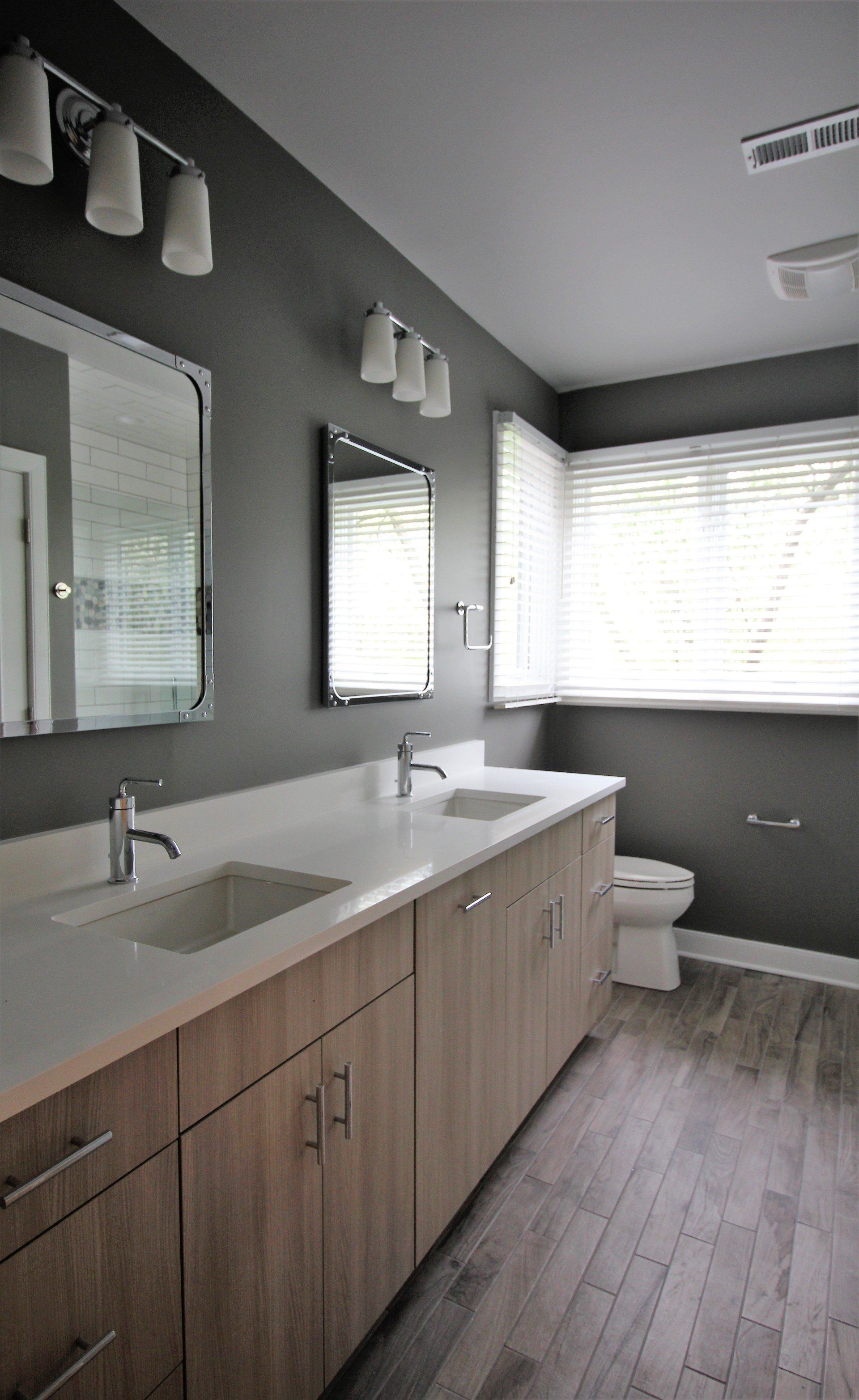 A bathroom with two sinks , a toilet and a mirror.