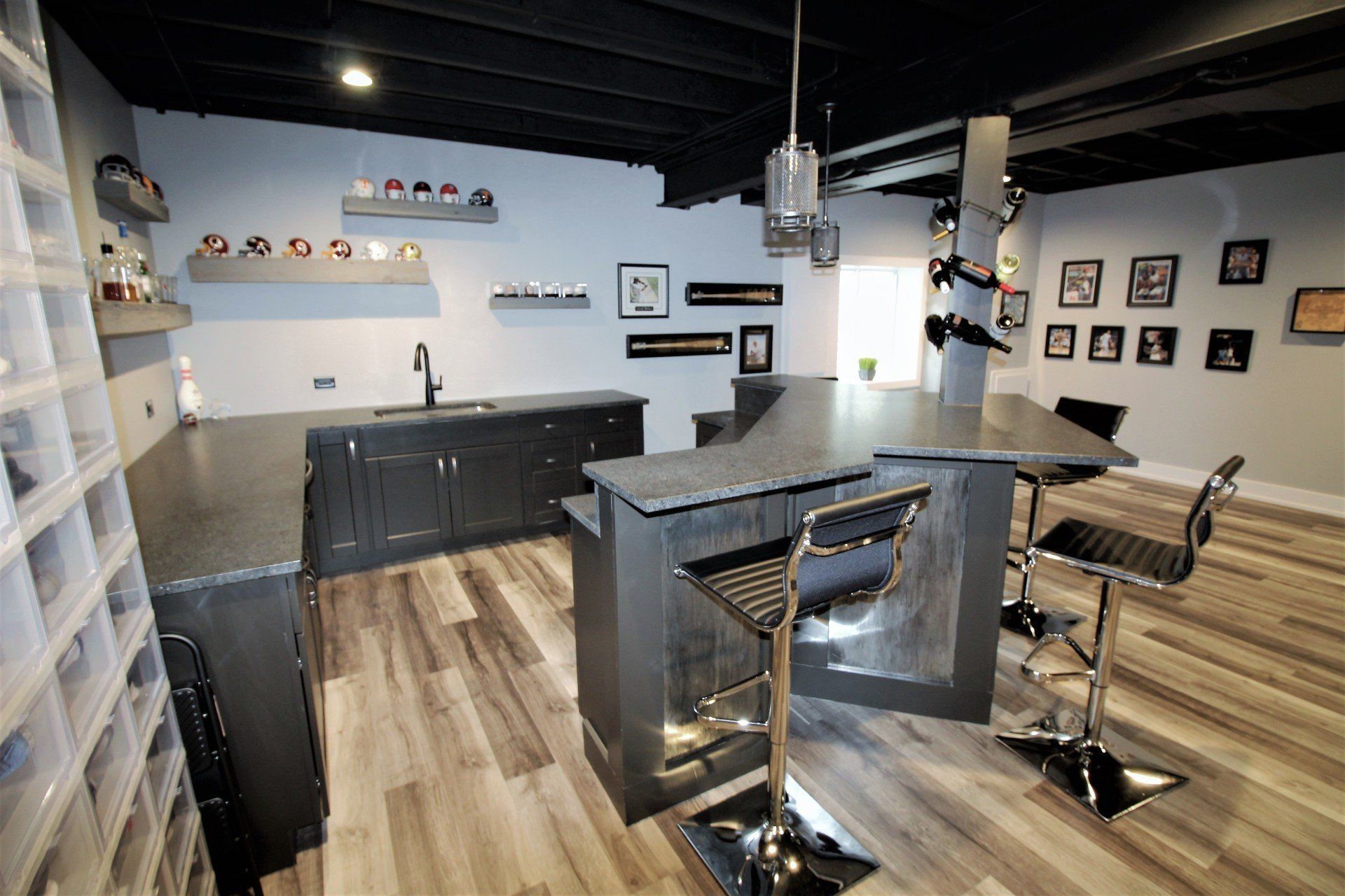 A kitchen with a large island and stools and a sink.