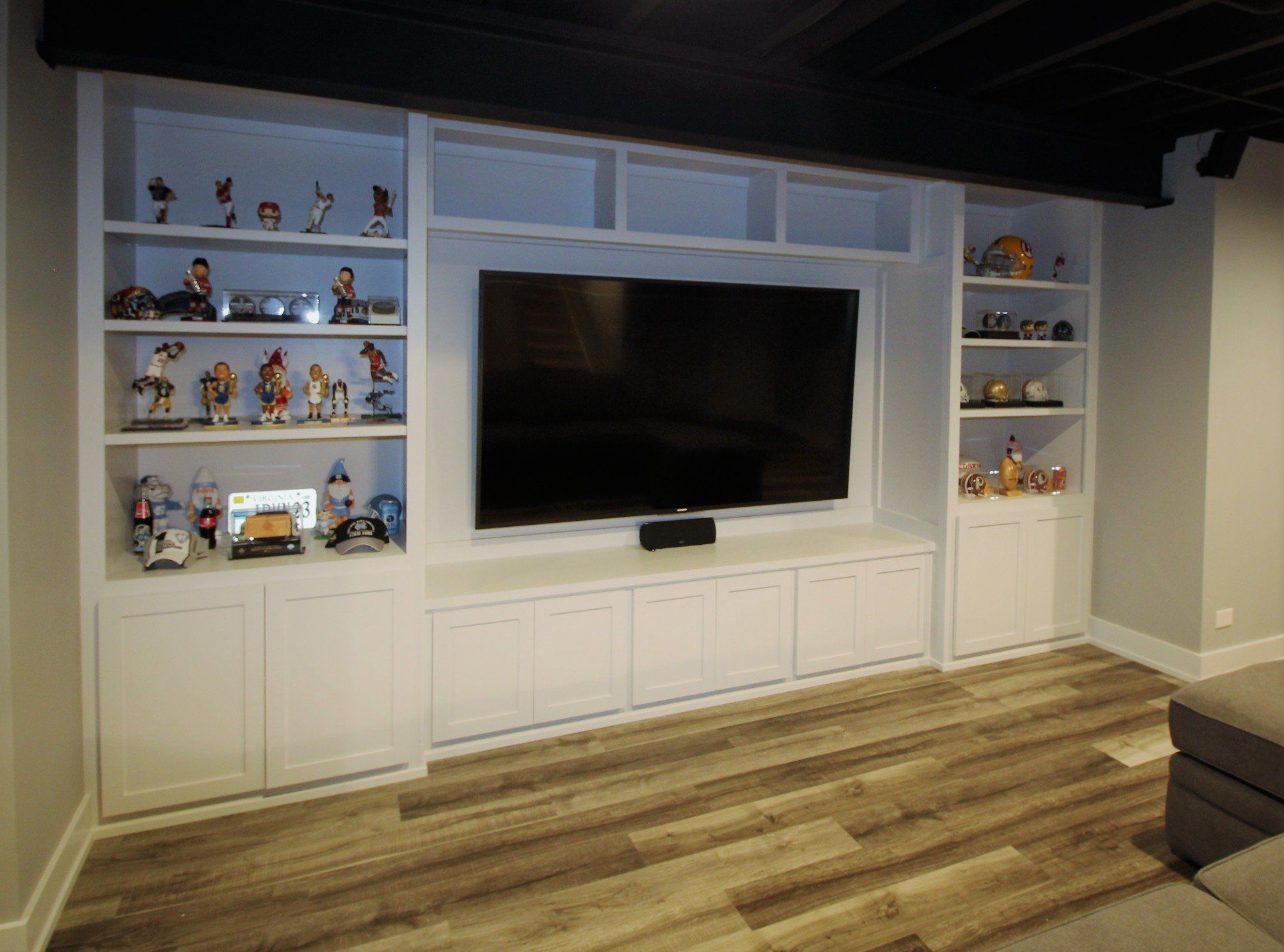 A living room with a flat screen tv and shelves.