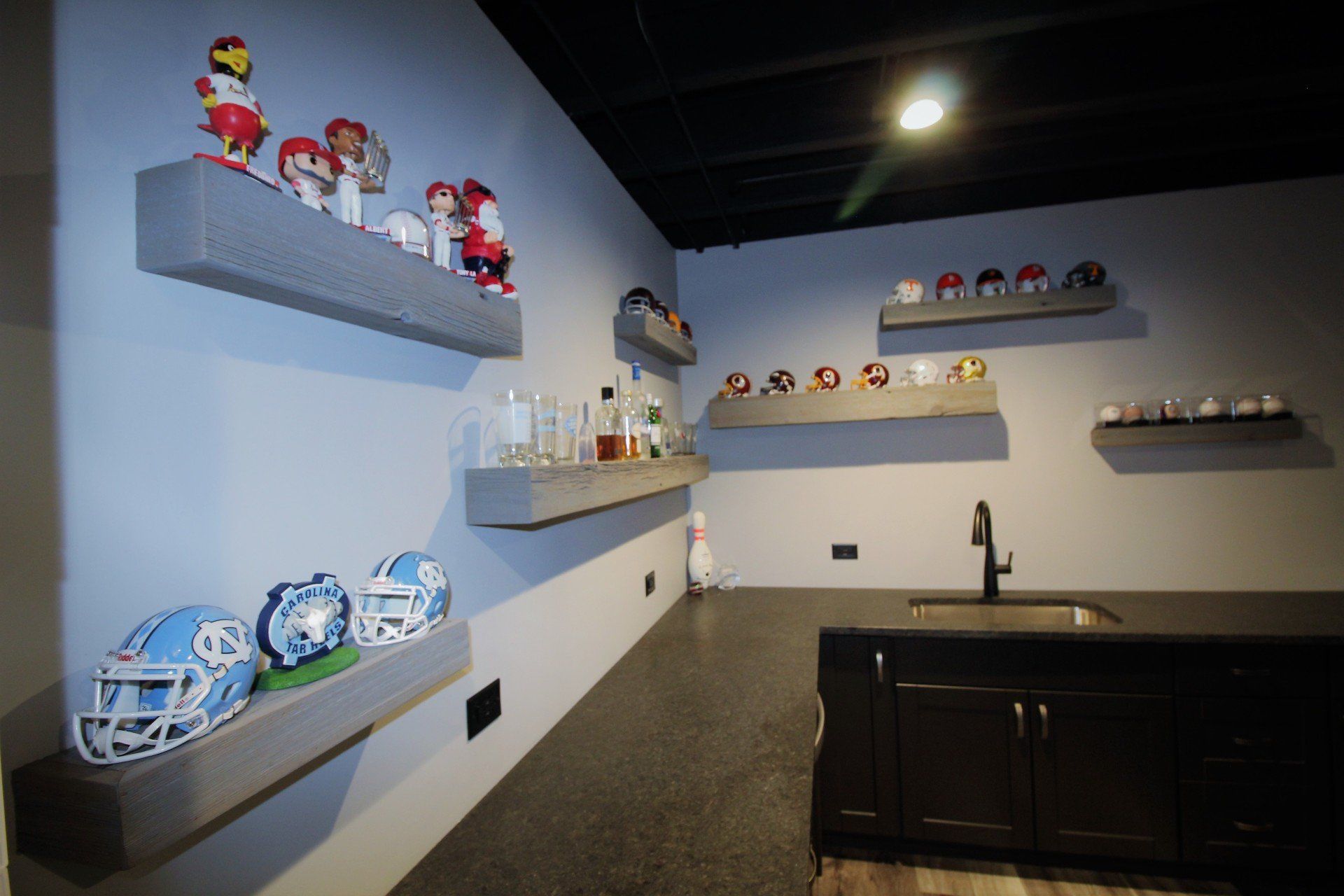 A kitchen with a sink and shelves filled with football helmets