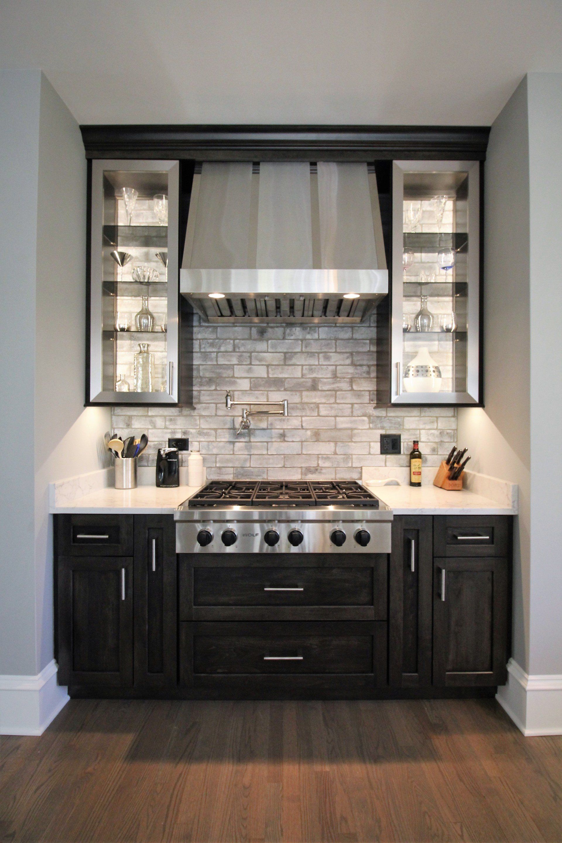 A kitchen with stainless steel appliances and black cabinets.