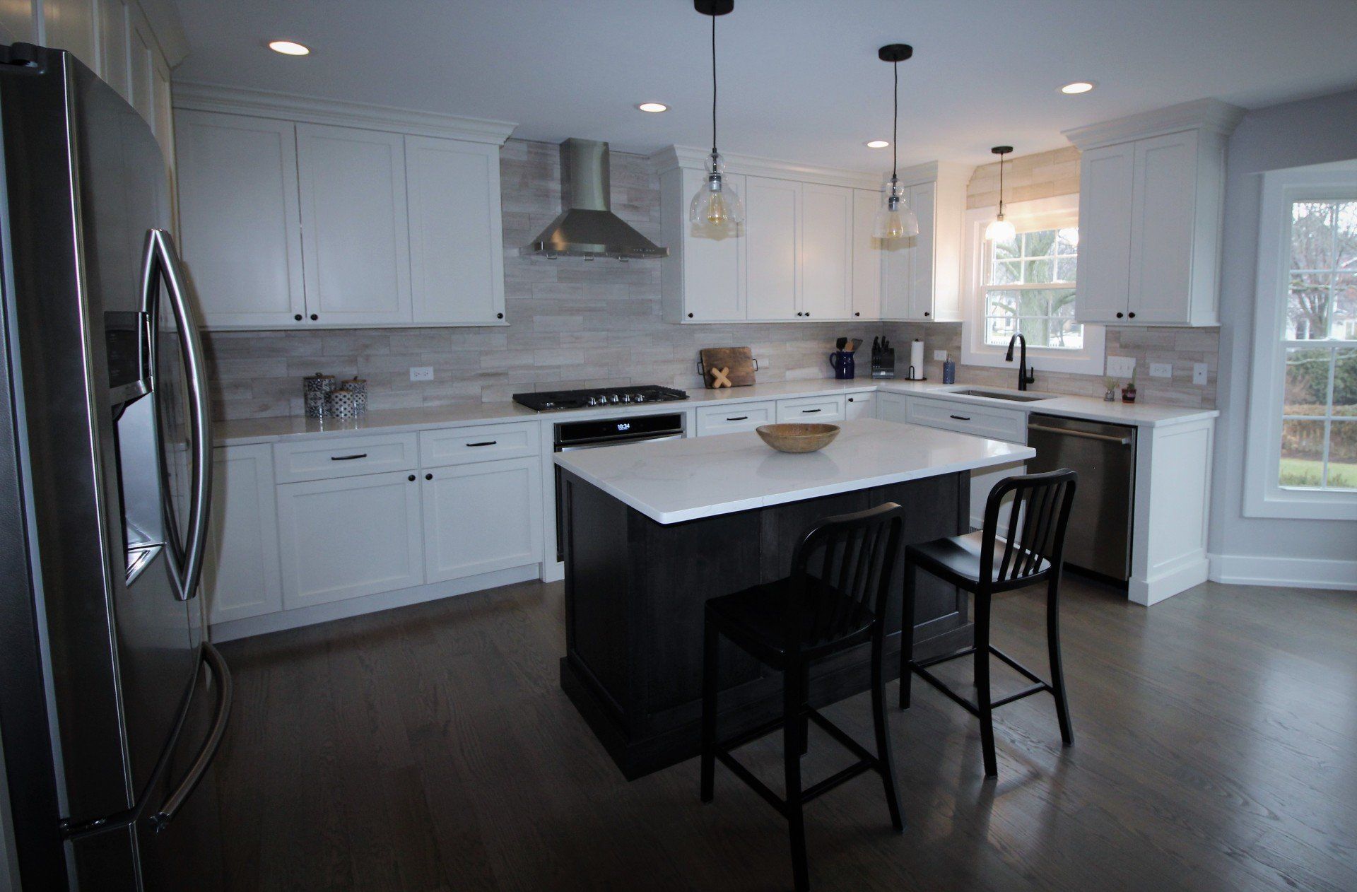 A kitchen with white cabinets , stainless steel appliances , and a large island.