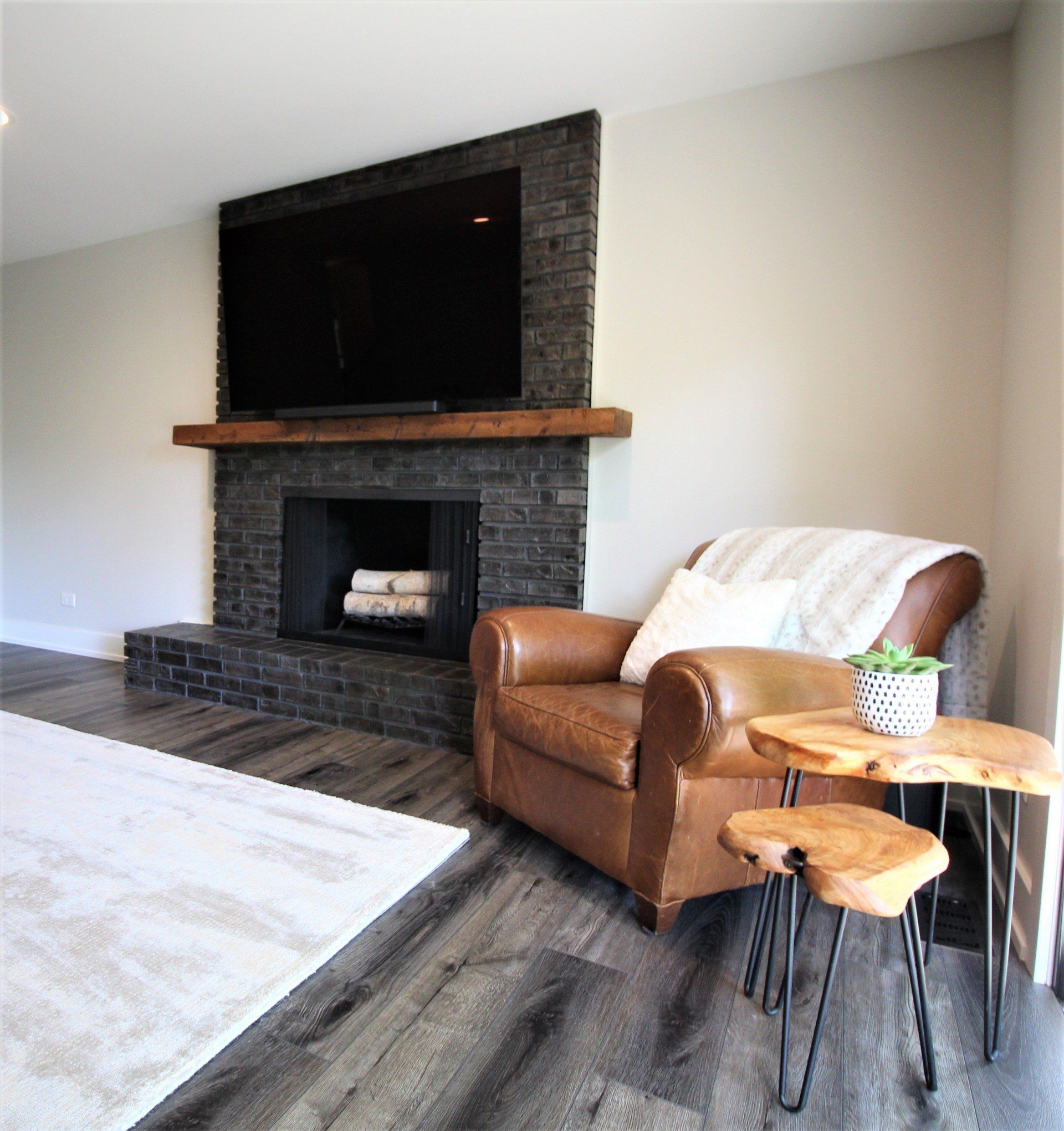 A living room with a fireplace , chair , table and television.