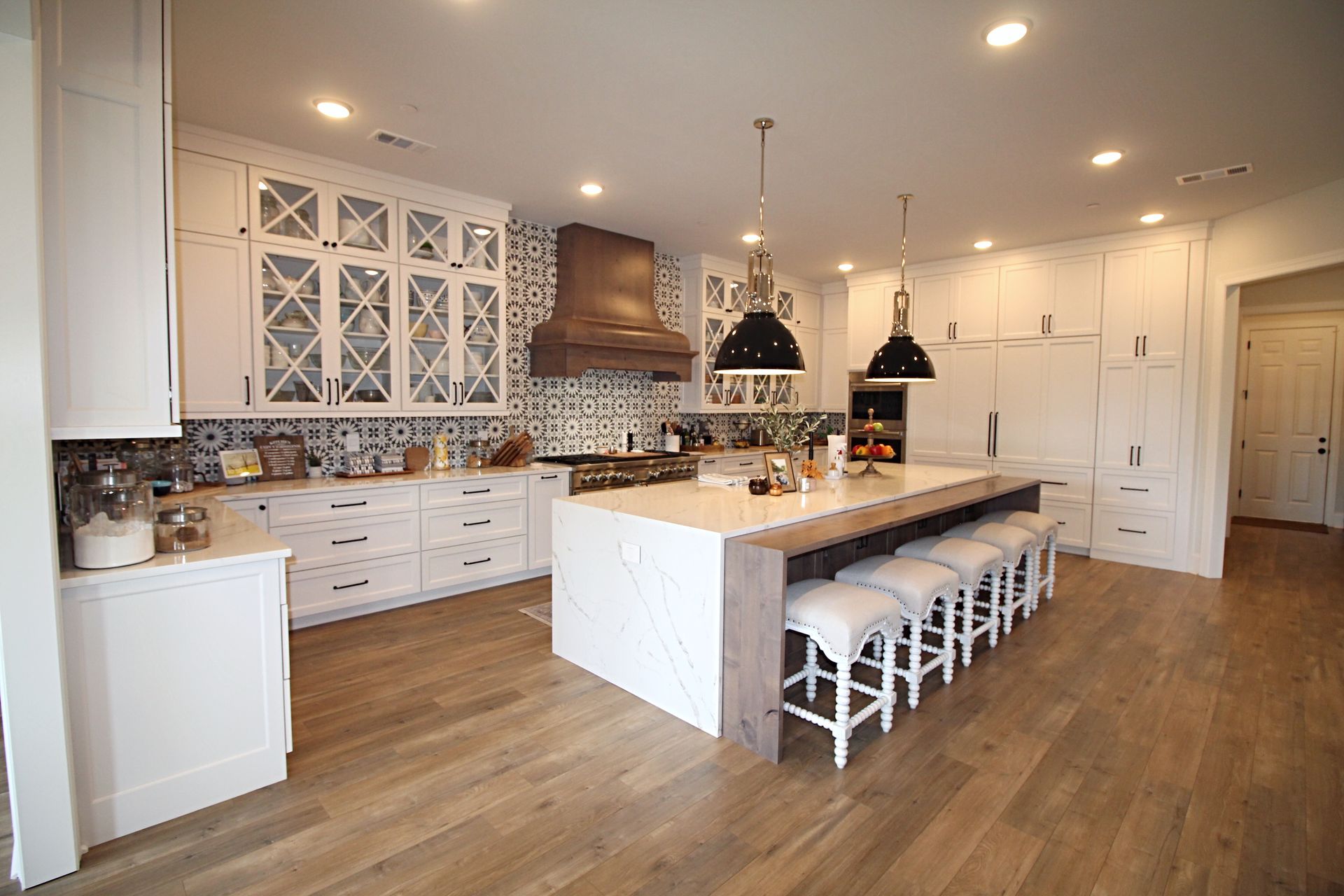 A large kitchen with white cabinets , hardwood floors , and a large island.