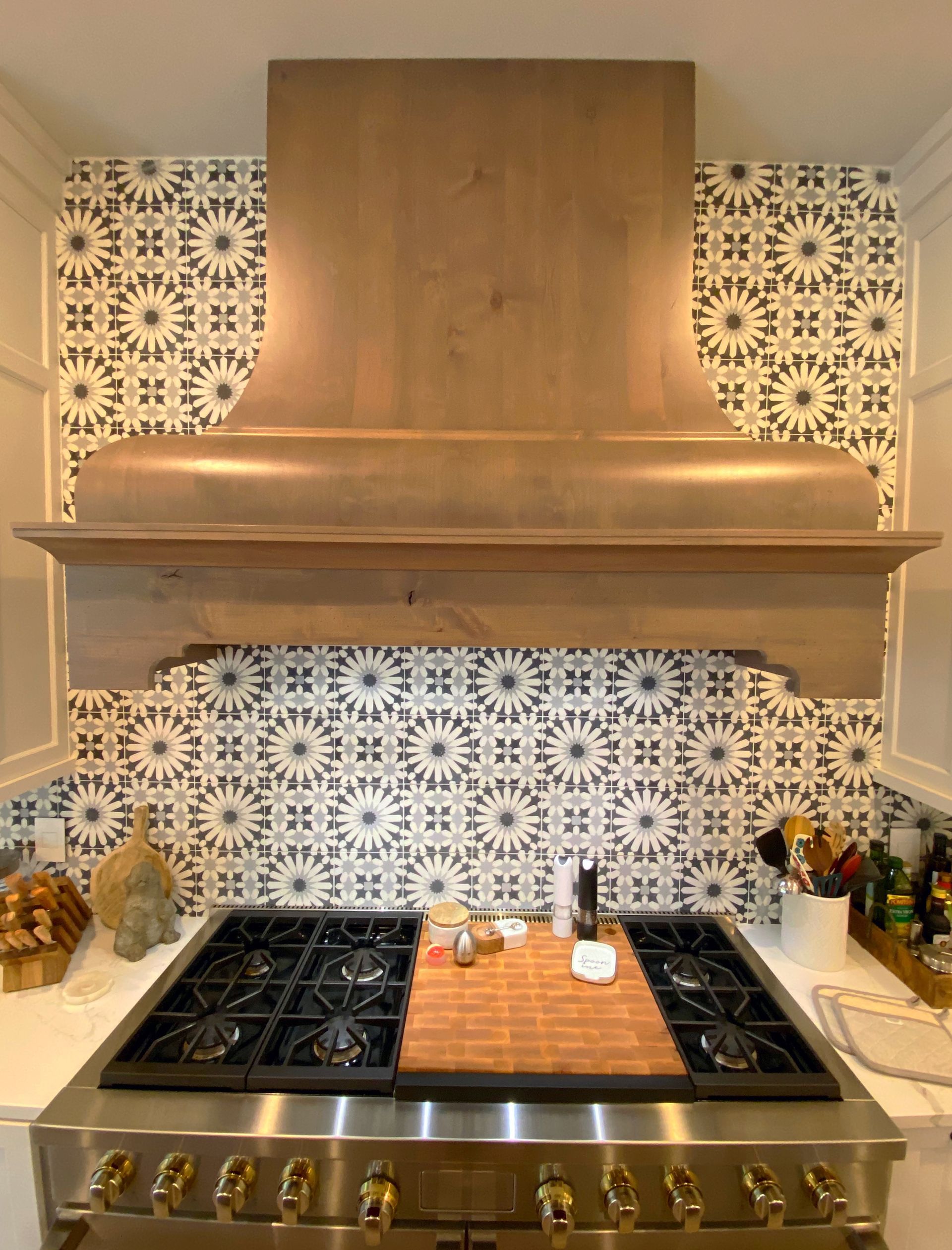 A stove top oven with a wooden hood above it in a kitchen.