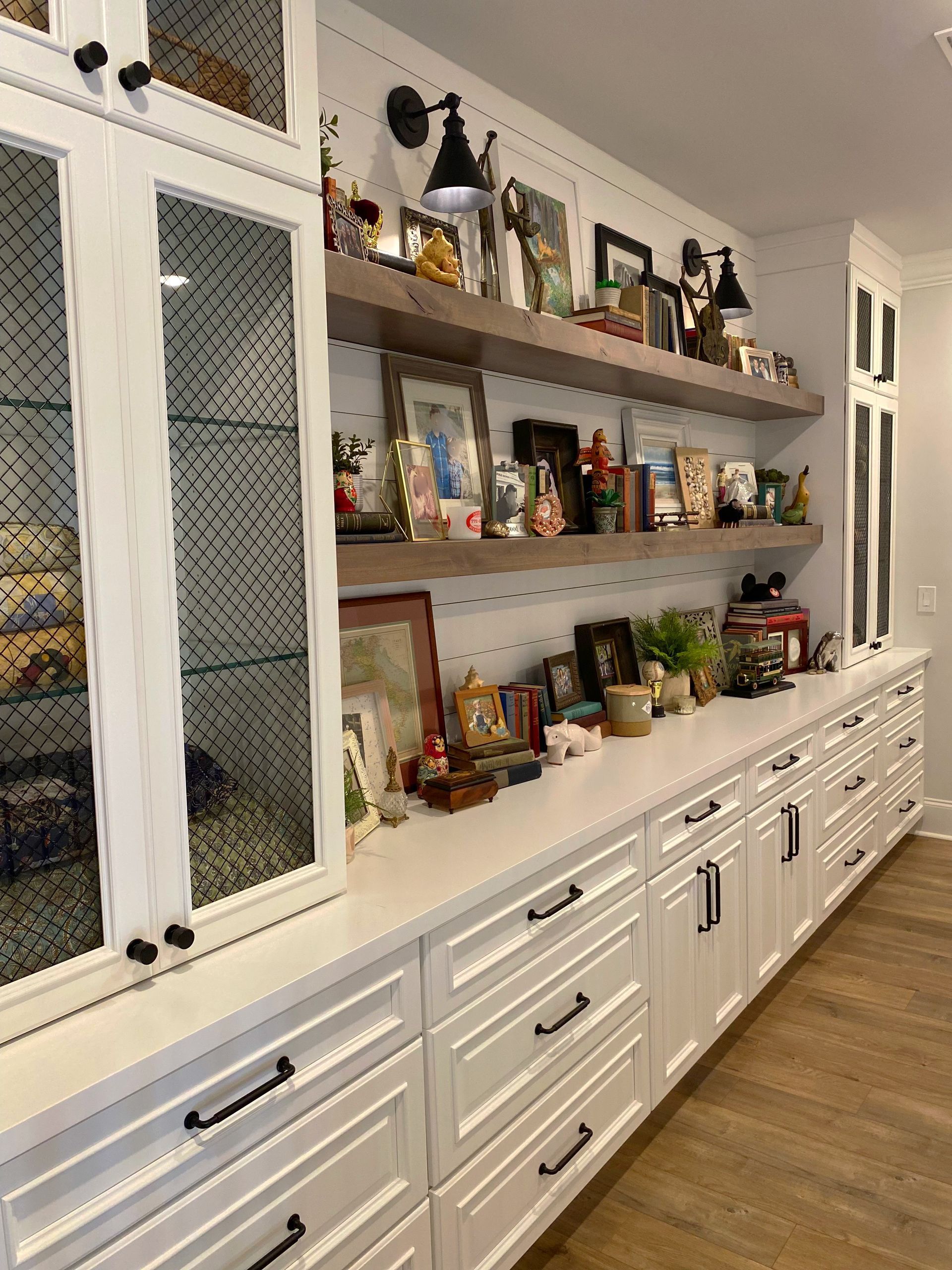 A kitchen with white cabinets , drawers and shelves filled with lots of items.