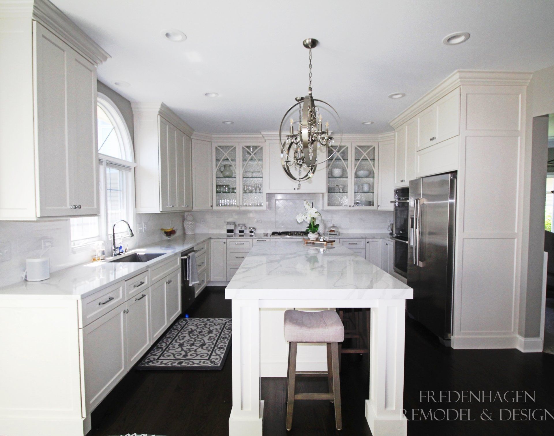A kitchen with white cabinets and marble counter tops