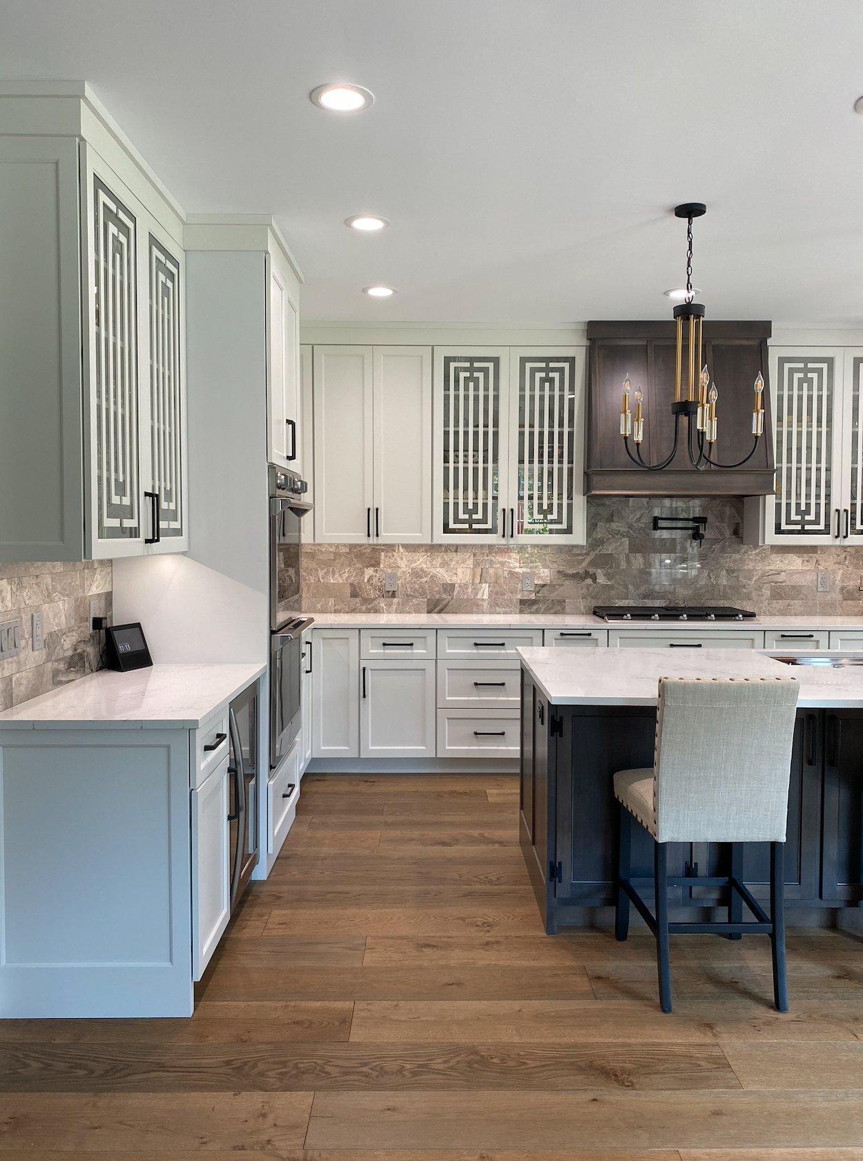 A kitchen with white cabinets , wooden floors , and a large island.
