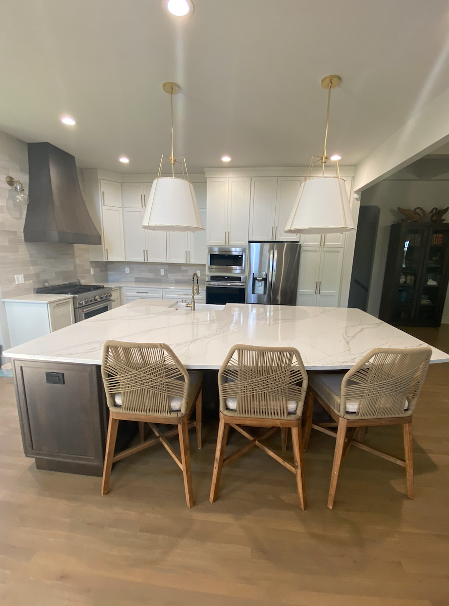 A kitchen with a large island and chairs in it.