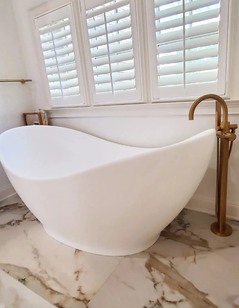 A white bathtub is sitting in a bathroom next to a window.