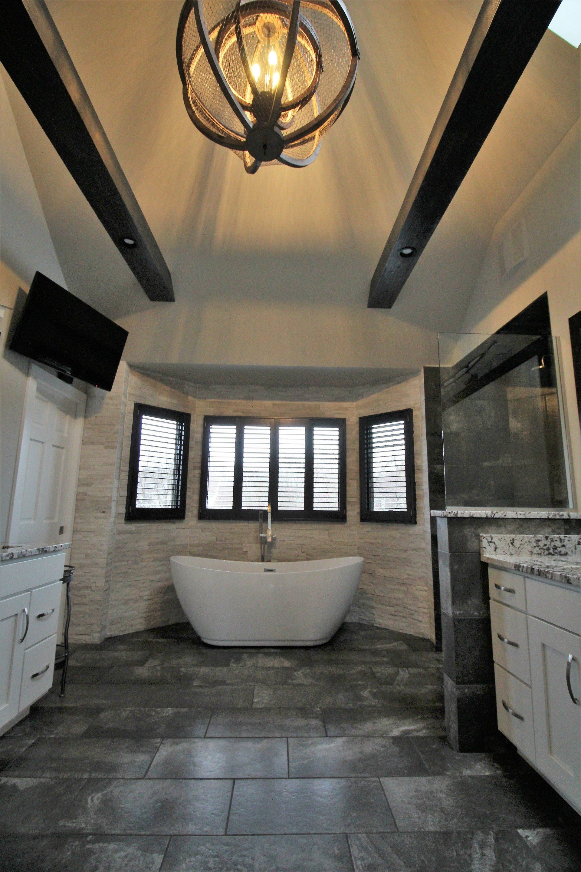 A bathroom with a bathtub and a chandelier hanging from the ceiling.
