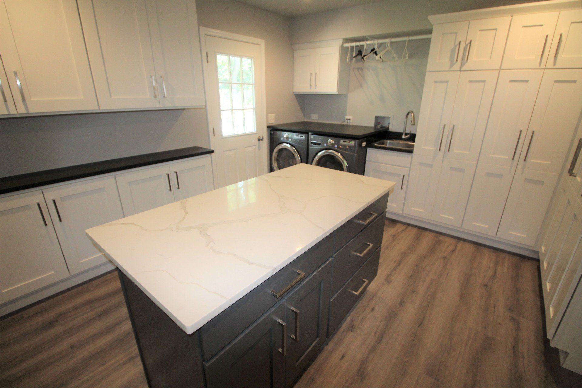 A laundry room with a large island in the middle and a washer and dryer.