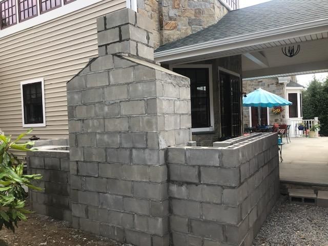A brick wall is being built on top of a grassy hill.