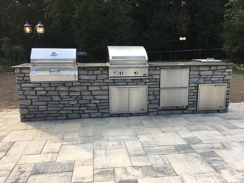 A man wearing red gloves is laying bricks on a sidewalk.