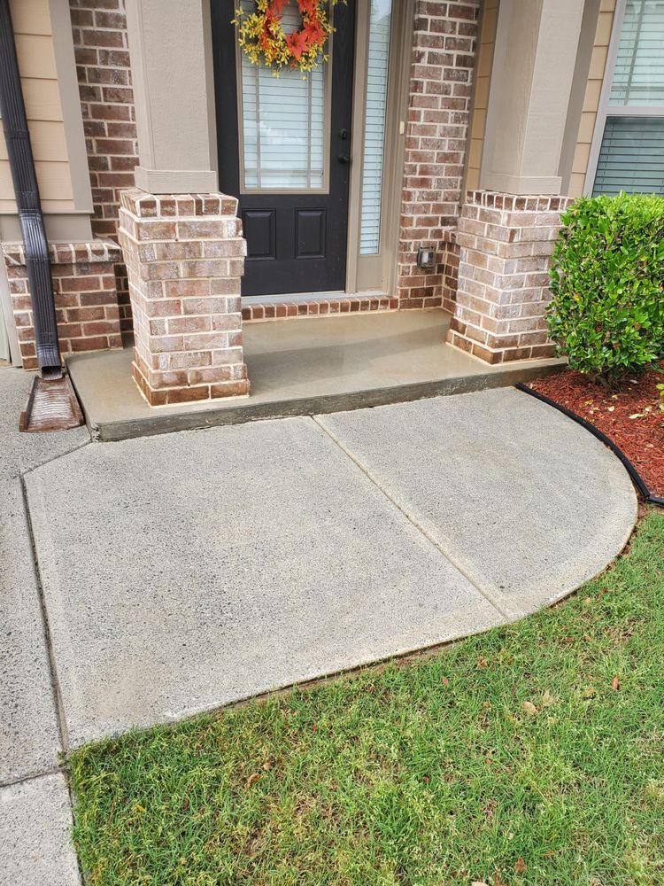 A brick house with a concrete walkway leading to the front door.