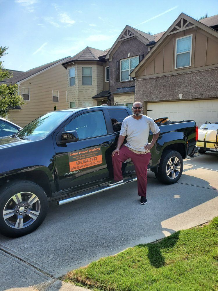 A man is standing next to a truck in front of a house.