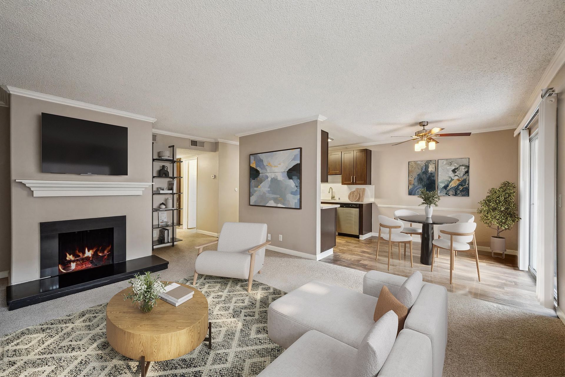 Open-concept living room with fireplace, wall-mounted TV, and dining area beside the kitchen.