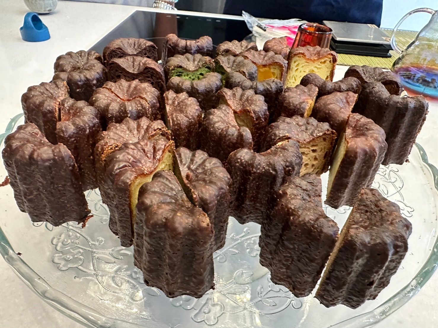 Chocolate pastries arranged on a glass platter, topped with green and yellow garnish.