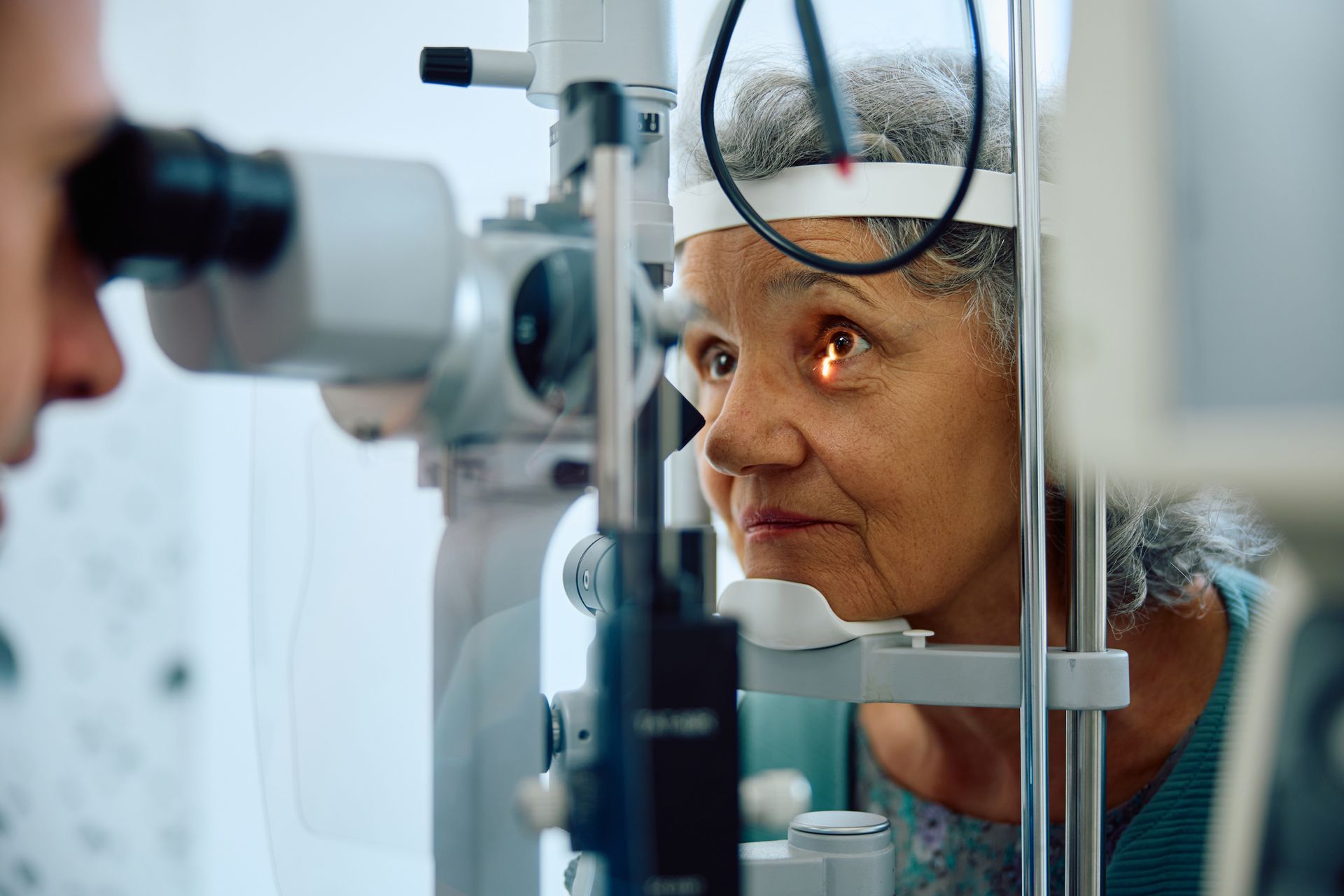 An ophthalmologist performing an eye exam on an elderly woman at an ophthalmology clinic. An ophthalmologist performing an eye exam on an elderly woman at an ophthalmology clinic.
