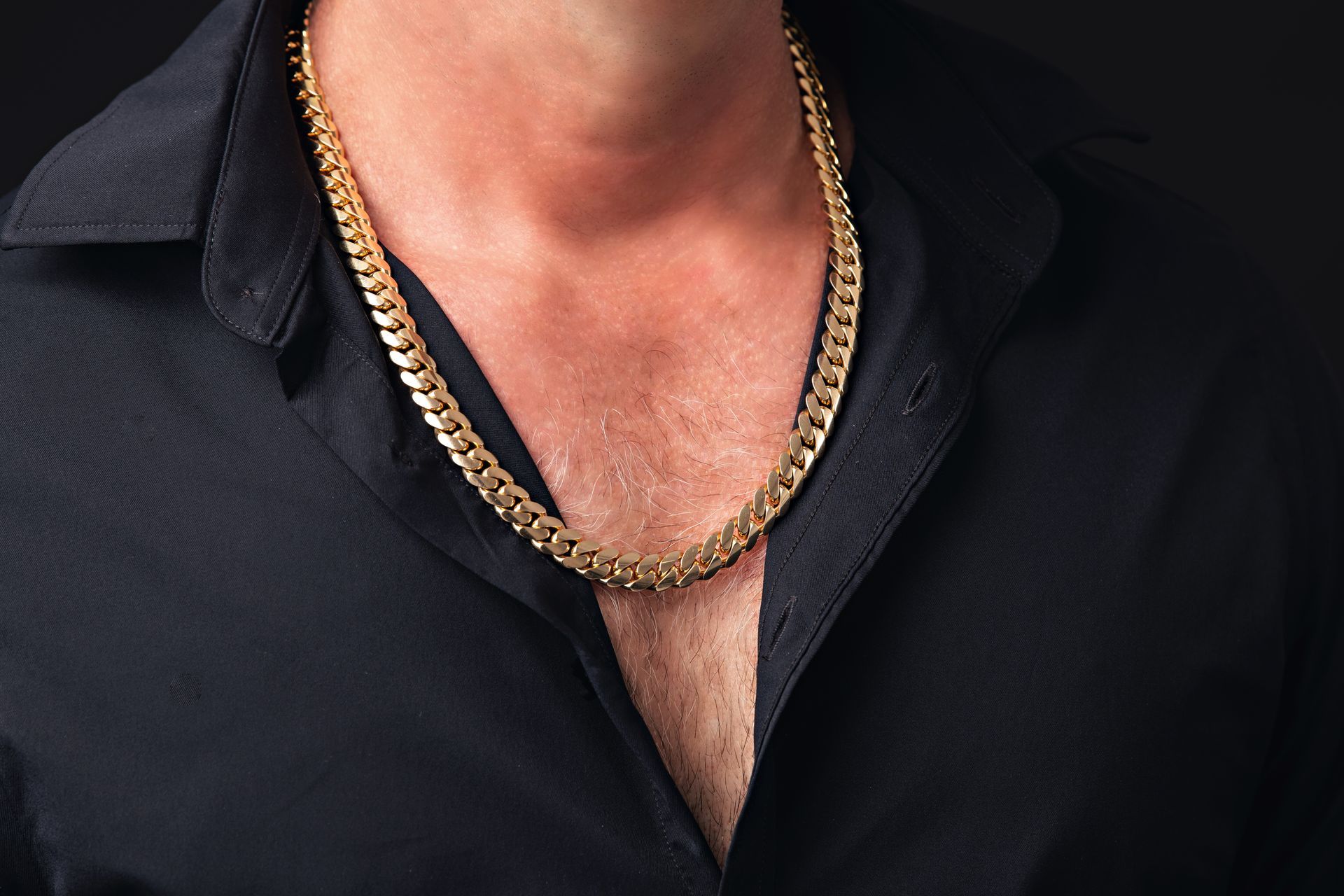Un hombre que llevaba una camisa negra y una cadena de oro alrededor de su cuello.