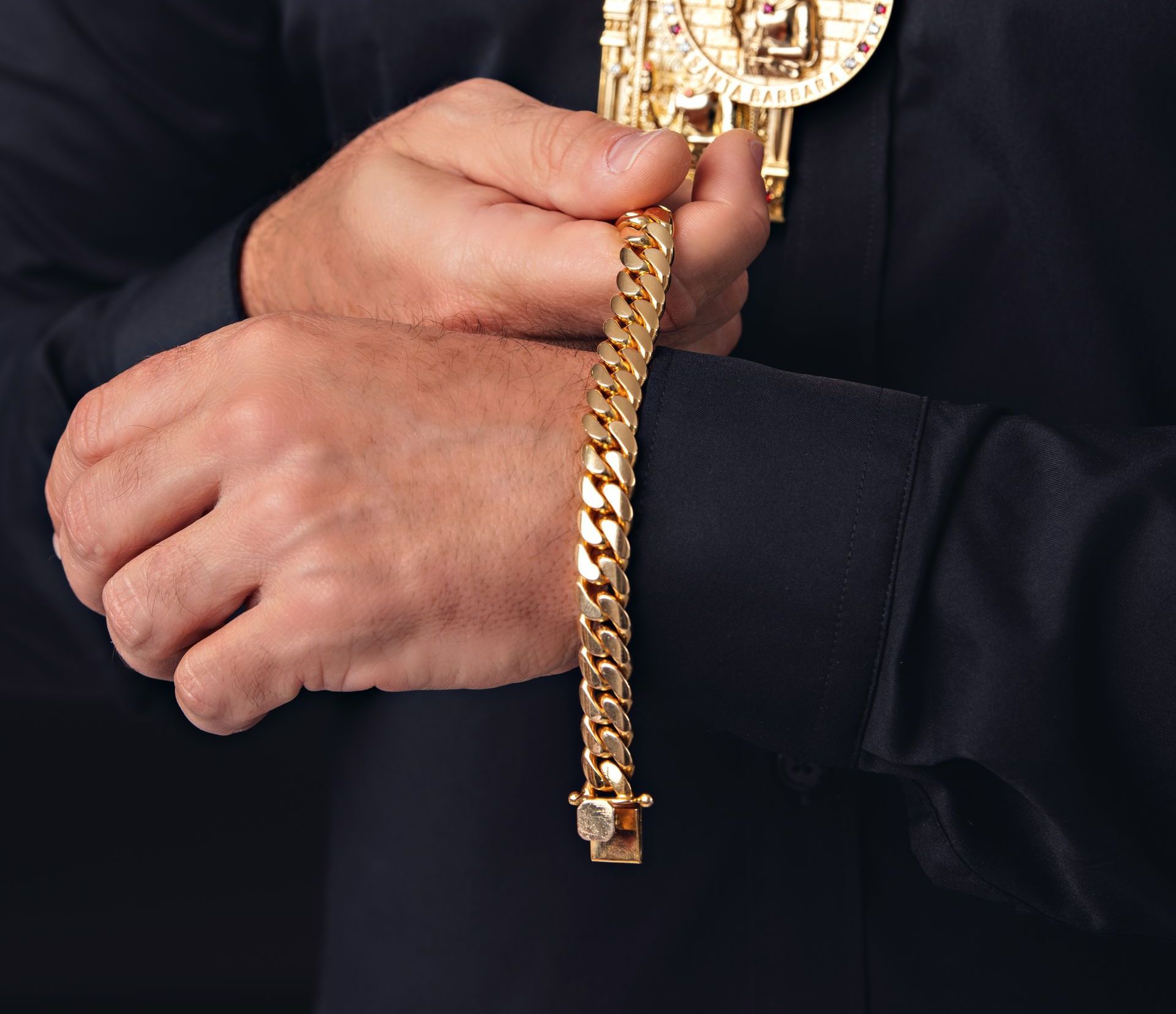 Un hombre sostiene una cadena de oro alrededor de su muñeca.