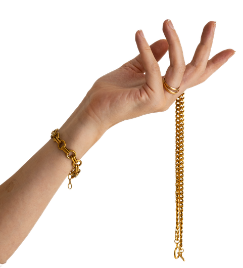 La mano de una mujer lleva una pulsera de oro y sostiene una cadena de oro.