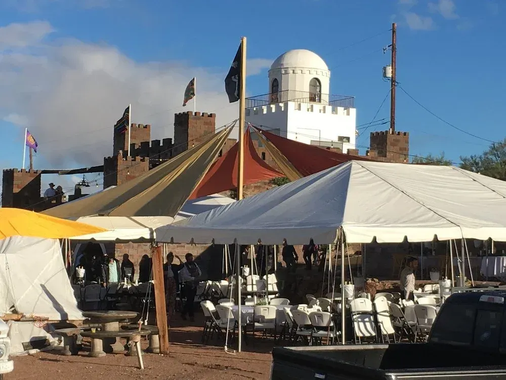 Castle-like structure with tents set up for an event, blue sky overhead.