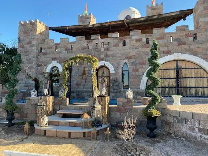 Stone castle-like building with arched entrance, topped with battlements and a wooden platform.