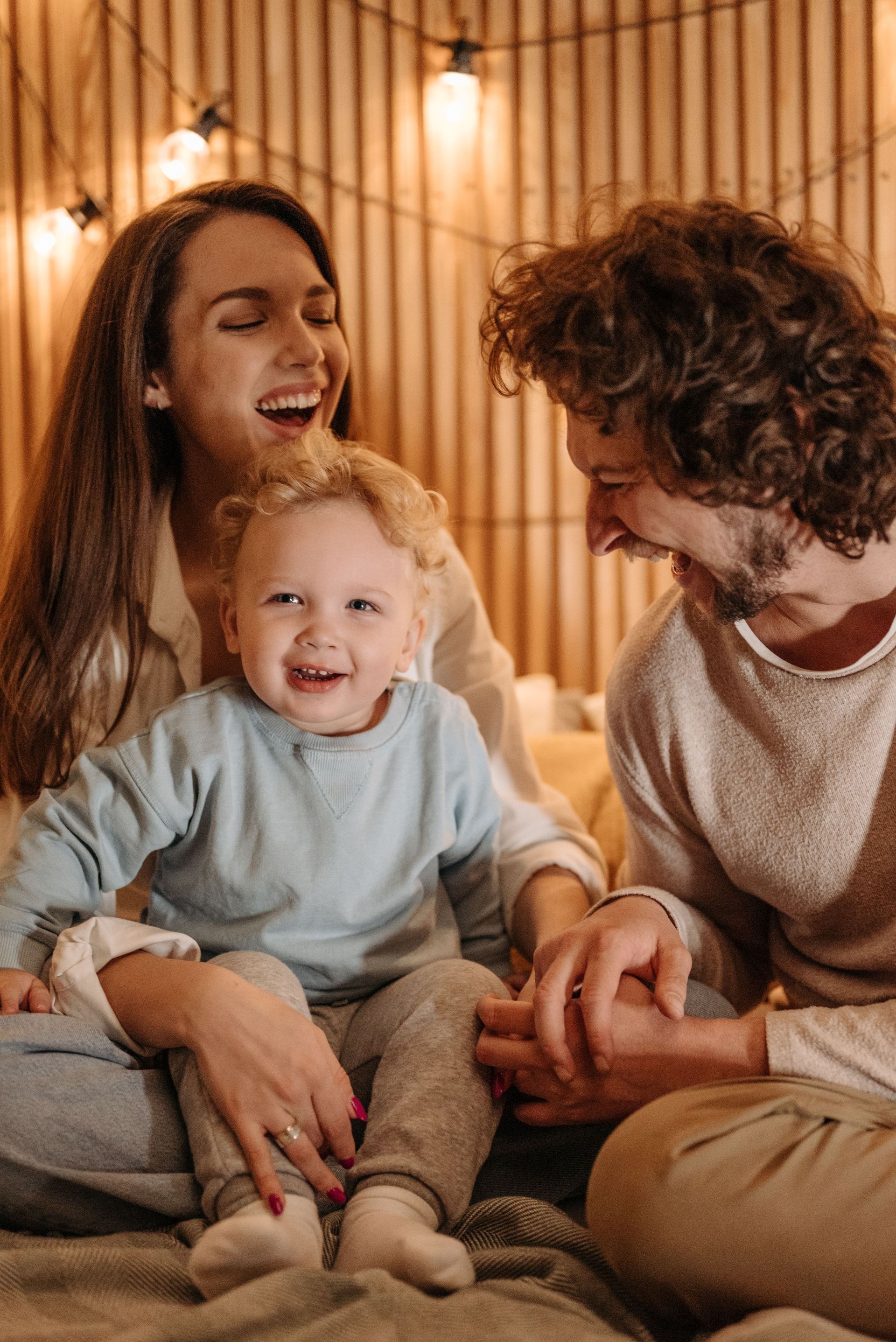 A family is sitting on the floor laughing and hugging each other.