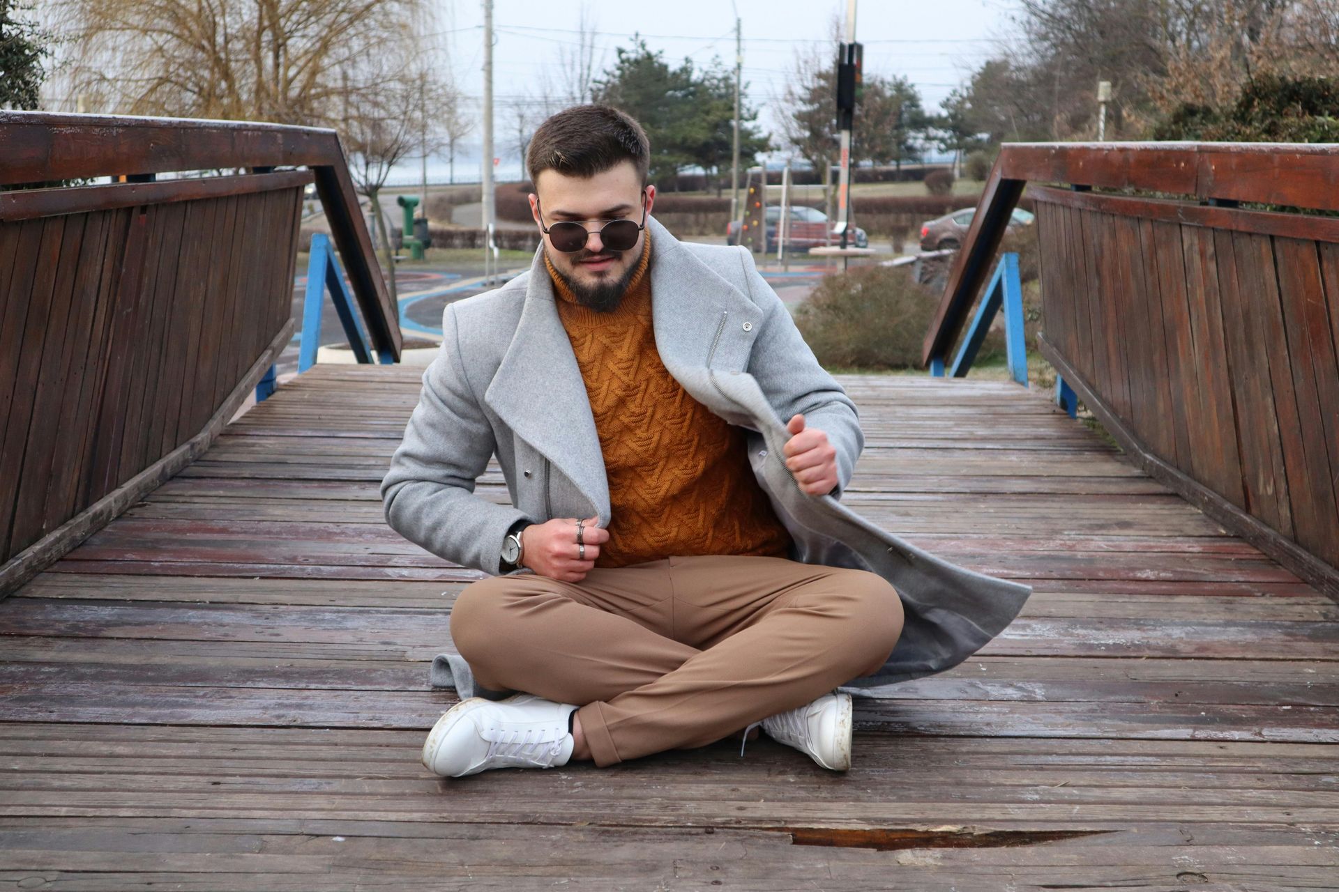 A man is sitting on a wooden bridge with his legs crossed.