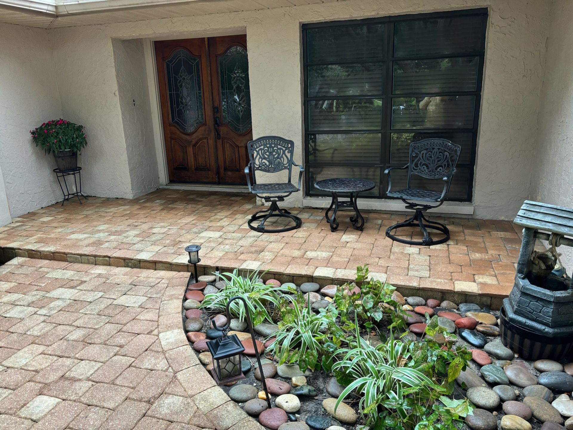 Brick patio with wooden door, three metal chairs, and a small garden with a wishing well.