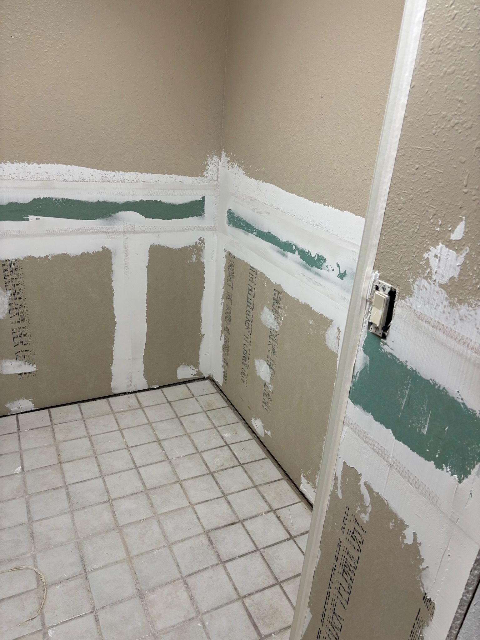 Bathroom renovation in progress, walls with partially installed drywall and green moisture-resistant board, white compound.