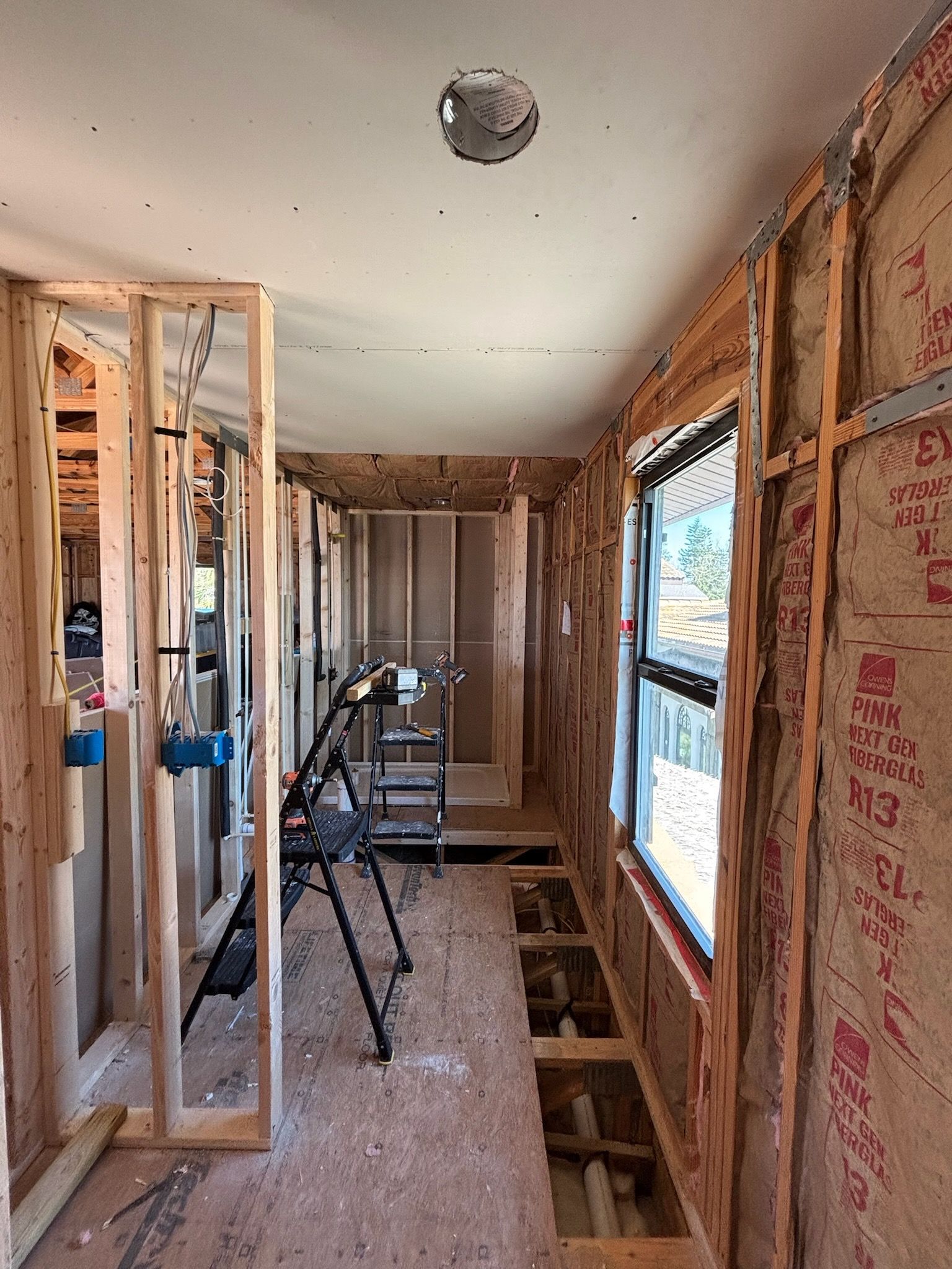 Interior room under construction with exposed wooden framing and a window.