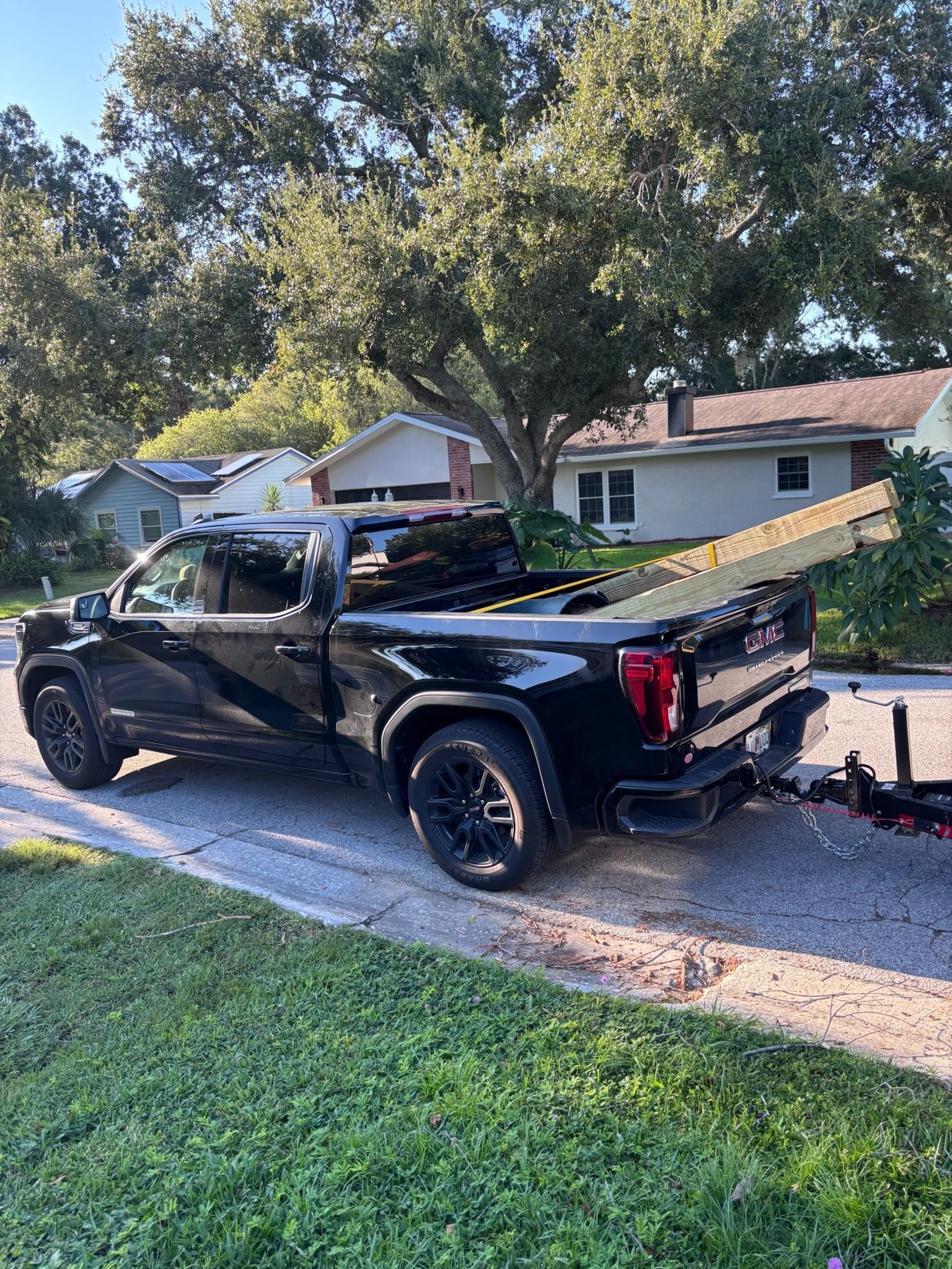Black pickup truck loaded with lumber parked on a residential street.