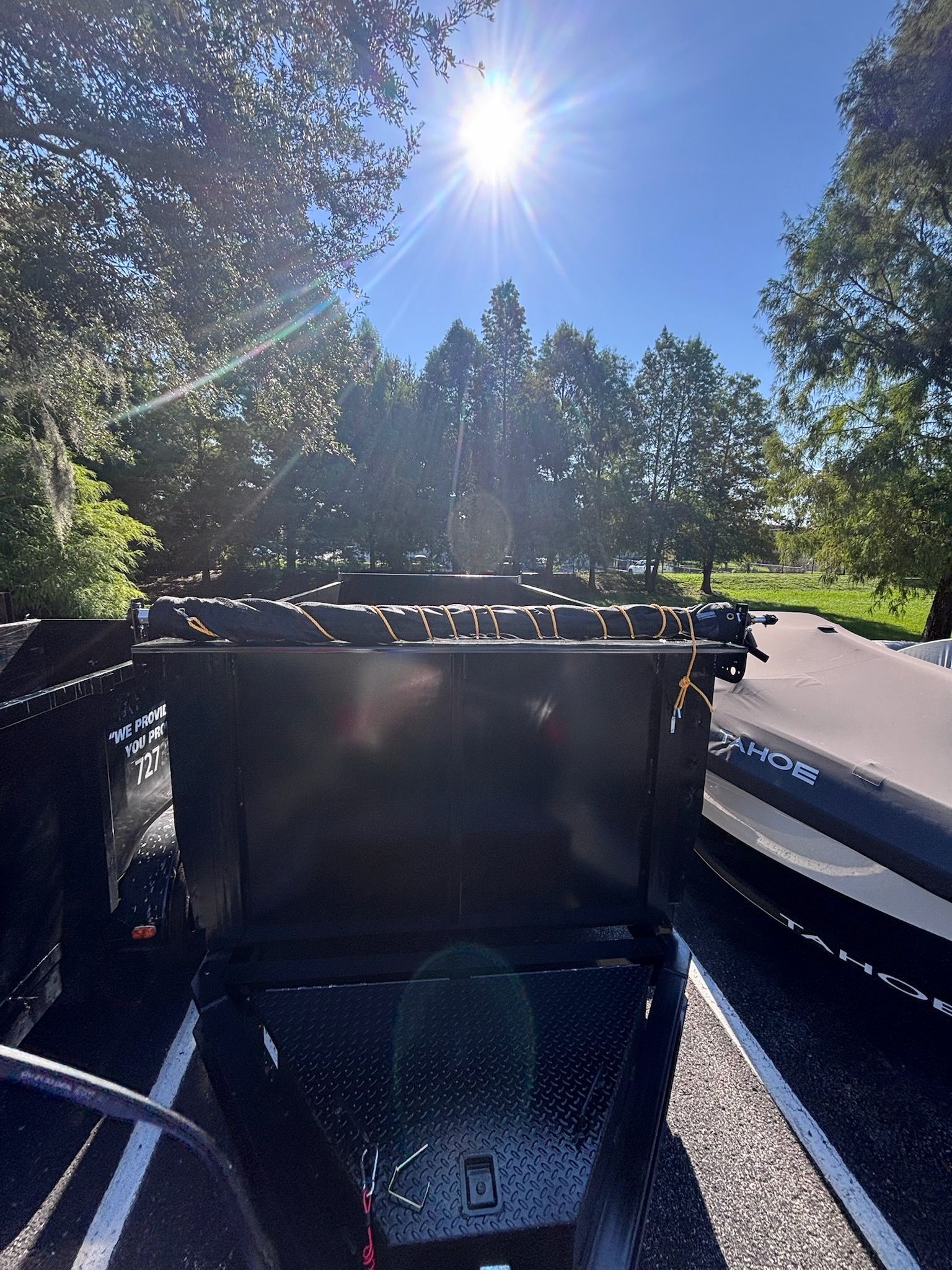 Black utility trailer with diamond plate on a sunny day.