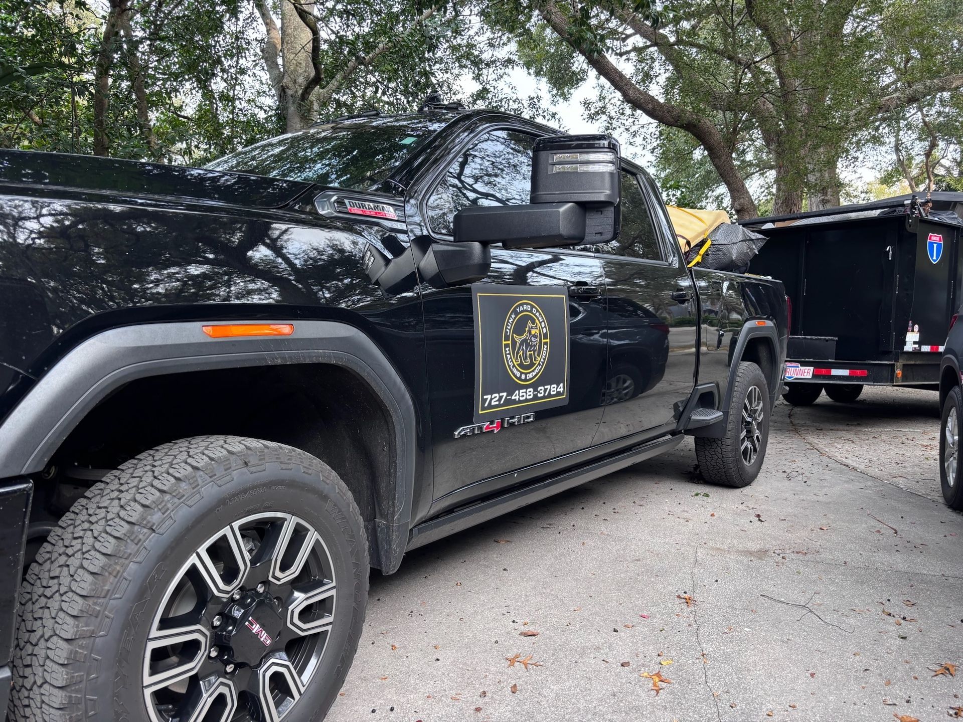Black pickup truck with trailer; logo on door. Parked outdoors.
