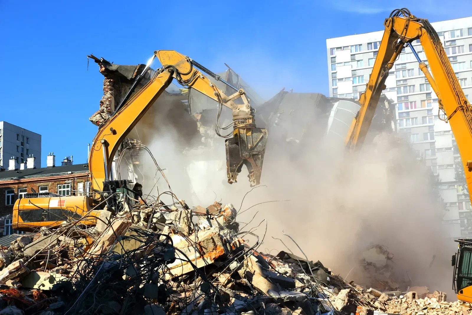 Two bulldozers are demolishing a building in a city.