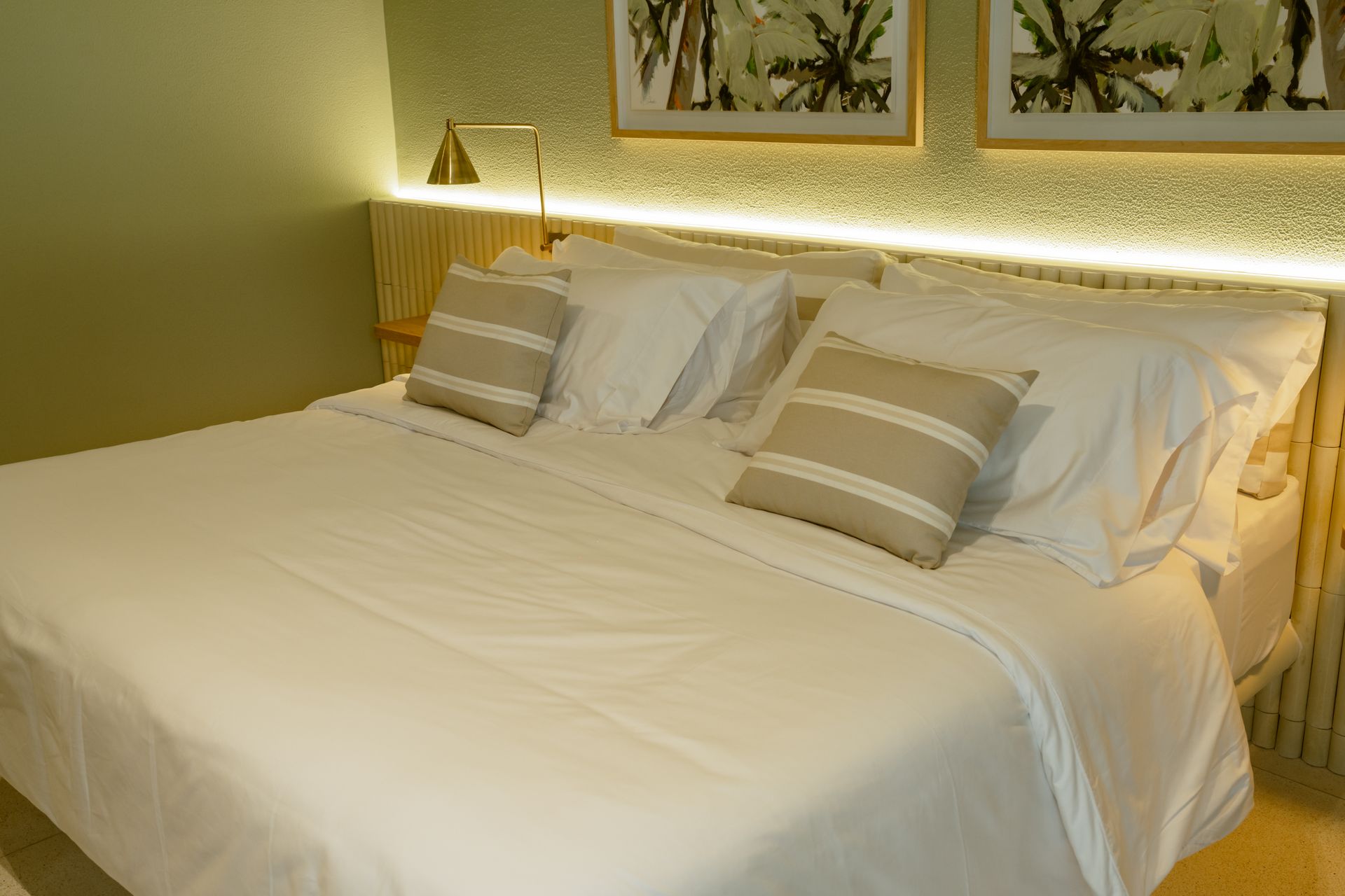 Una cama con sábanas blancas y almohadas en una habitación de hotel.