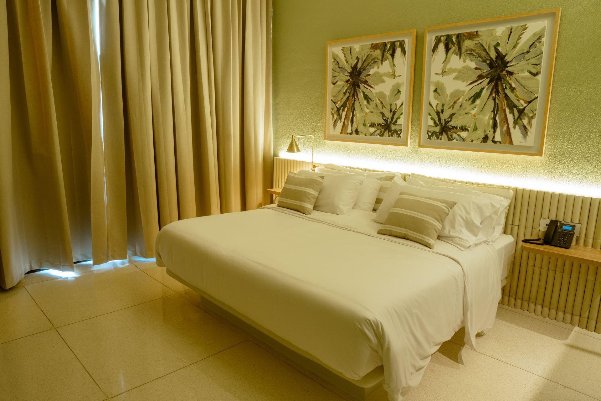 Una habitación de hotel con una cama tamaño king y dos cuadros en la pared.