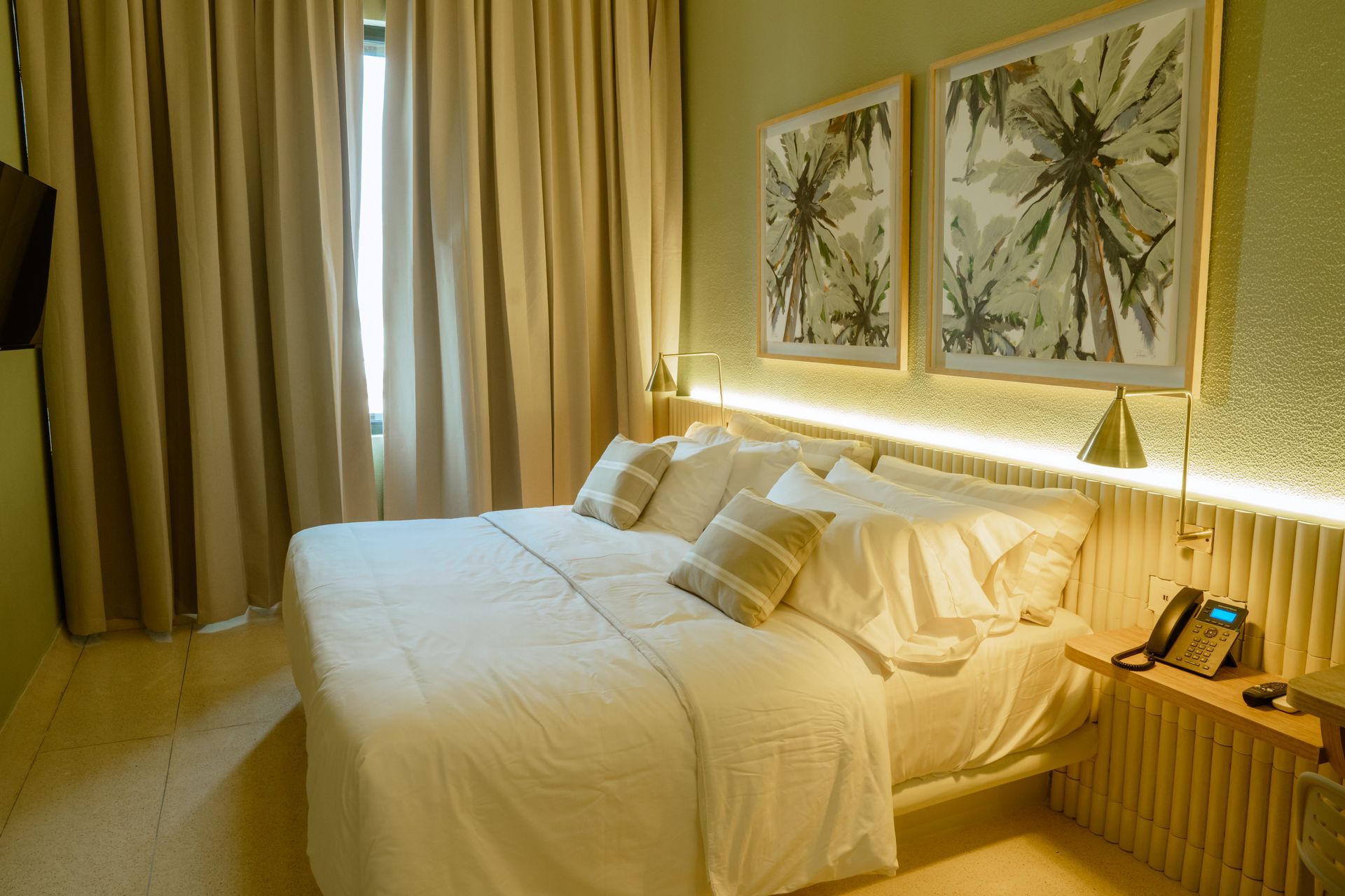 Una habitación de hotel con una cama tamaño king y dos cuadros en la pared.