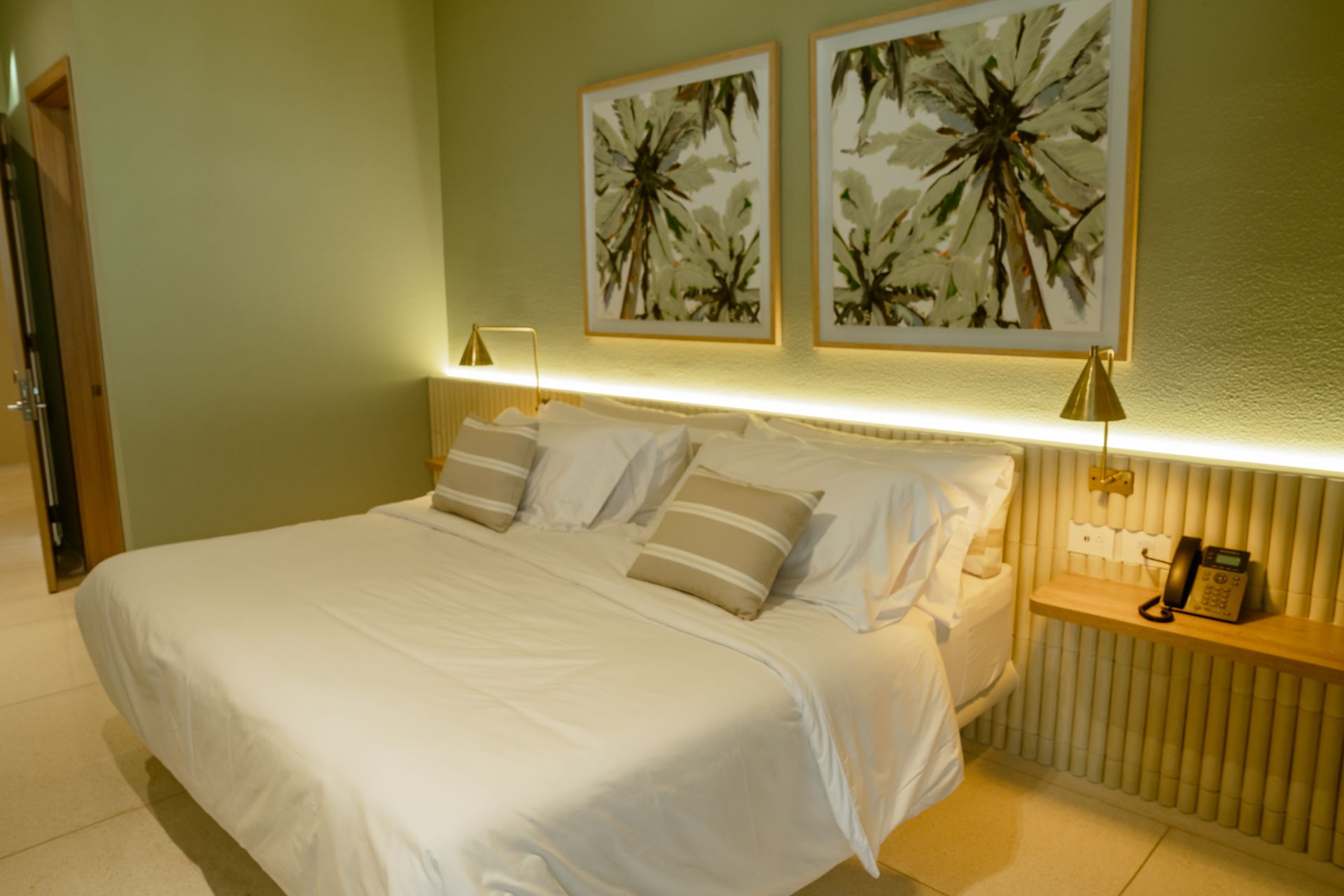 Una habitación de hotel con una cama grande y dos cuadros en la pared.