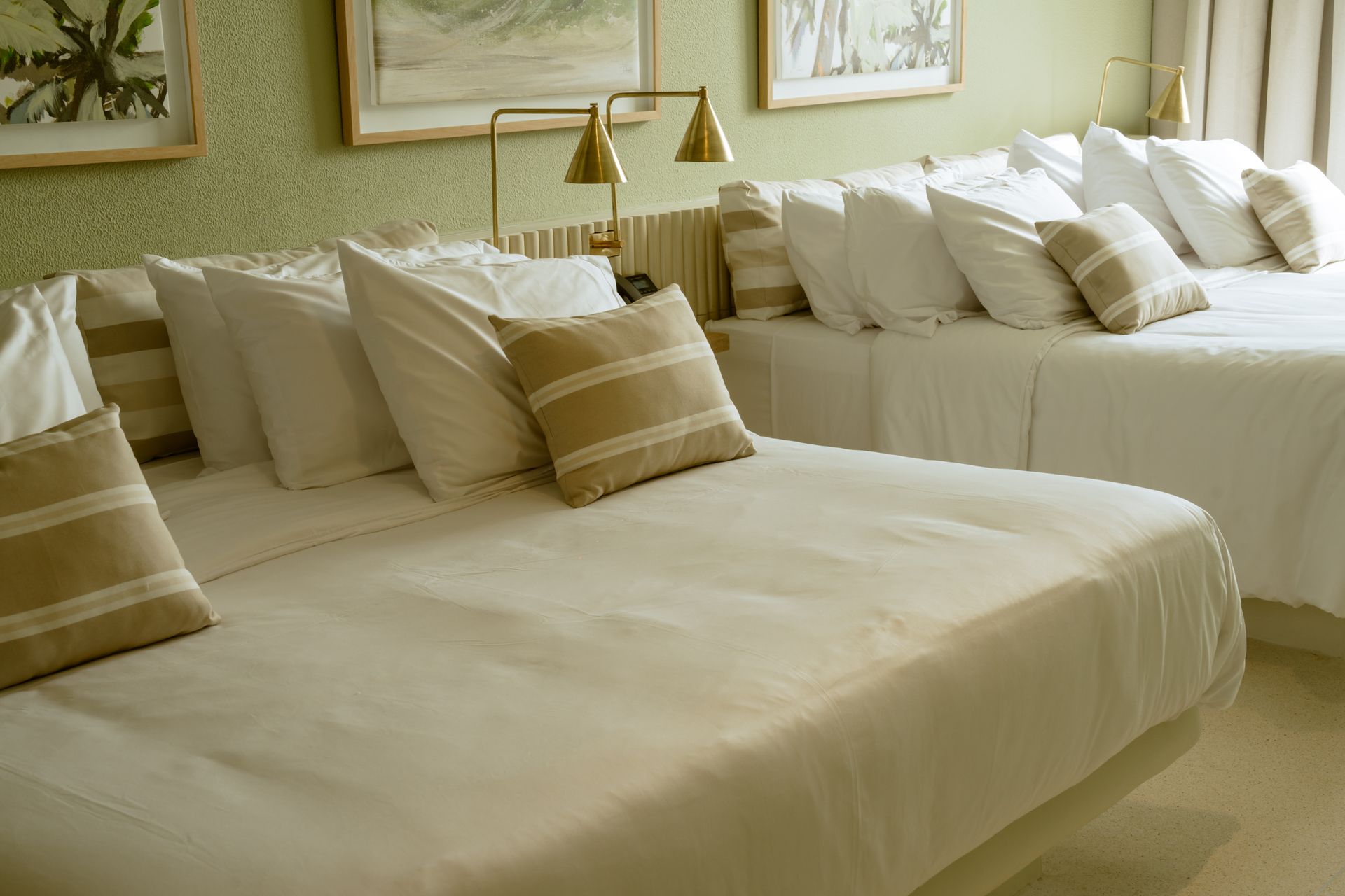 Hay dos camas en una habitación de hotel con sábanas y almohadas blancas.